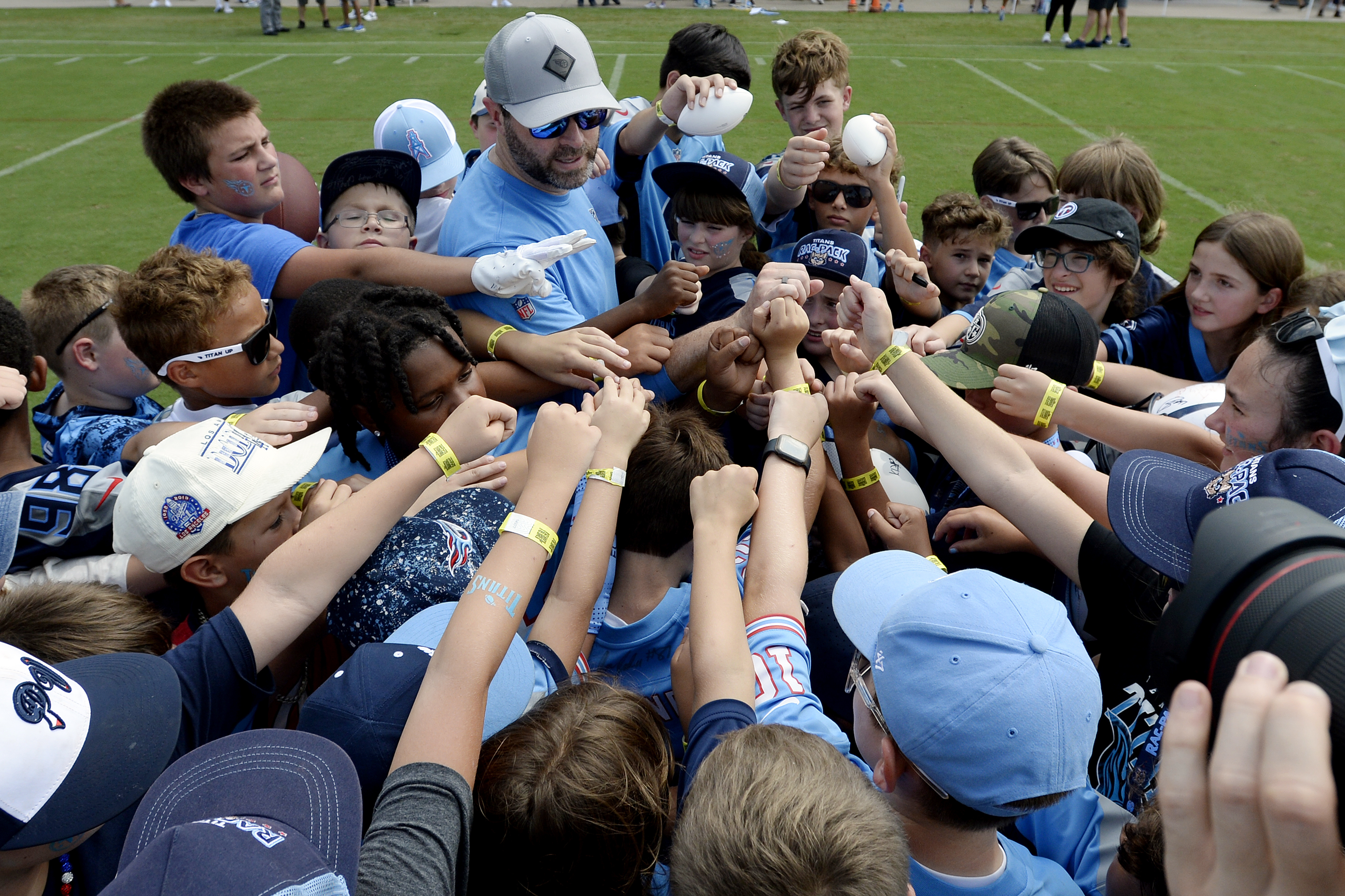 Tennessee Titans head coach Brian Callahan huddles with a group of children on the field after practice at NFL football training camp, Tuesday, July, 30, 2024, in Nashville, Tenn. Callahan spent time talking to them and answers questions. 
