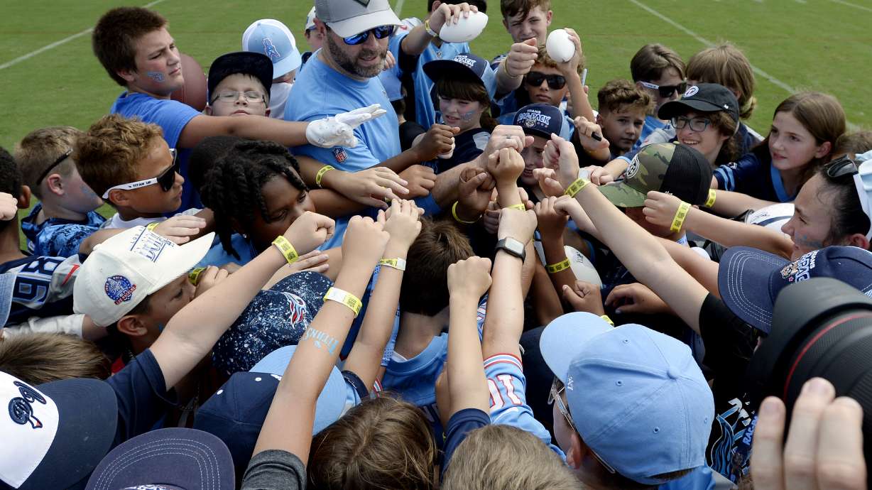 Tennessee Titans head coach Brian Callahan huddles with a group of children on the field after practice at NFL football training camp, Tuesday, July, 30, 2024, in Nashville, Tenn. Callahan spent time talking to them and answers questions.