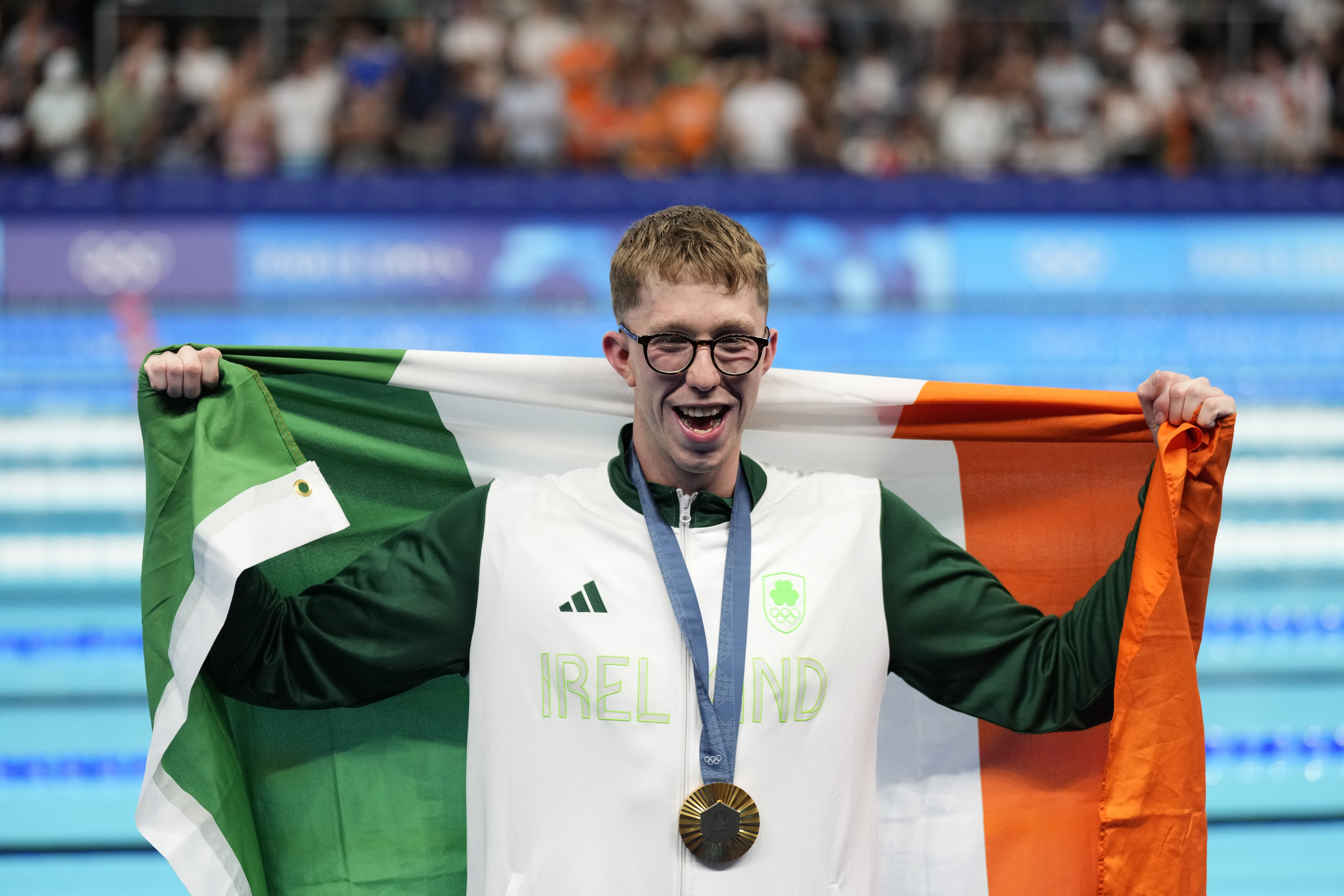 Gold medalist Daniel Wiffen, of Ireland, poses for a photo with his national flag on the podium following the men's 800-meter freestyle final at the 2024 Summer Olympics, Tuesday, July 30, 2024, in Nanterre, France. 