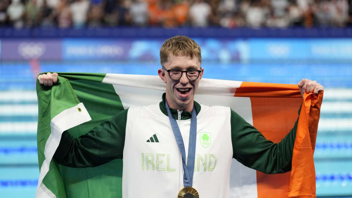 Gold medalist Daniel Wiffen, of Ireland, poses for a photo with his national flag on the podium following the men's 800-meter freestyle final at the 2024 Summer Olympics, Tuesday, July 30, 2024, in Nanterre, France.