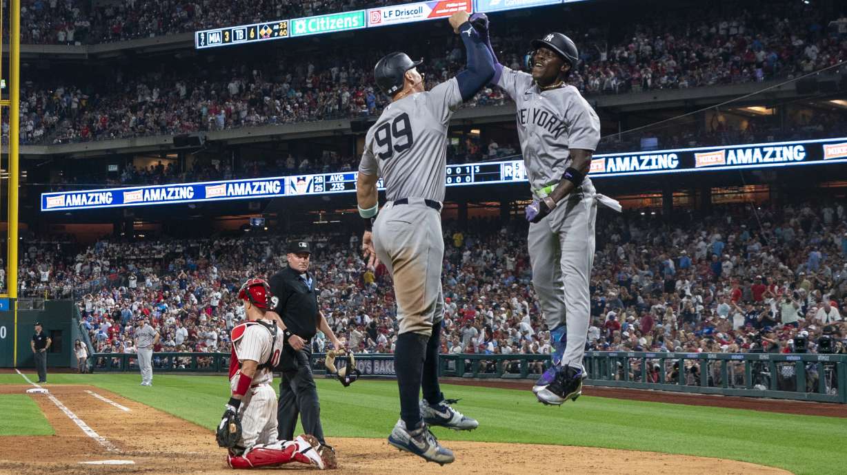 New York Yankees' Jazz Chisholm Jr., right, celebrates his three-run home run with Aaron Judge, center, as Philadelphia Phillies catcher J.T. Realmuto, left, looks on during the seventh inning of a baseball game, Tuesday, July 30, 2024, in Philadelphia.