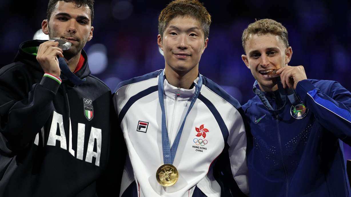 Hong Kong's Cheung Ka long, centre, winner of the gold medal in the men's individual Foil competition, celebrates on the podium with silver medal winner Italy's Filippo Macchi, left, and bronze medal winner United State's Nick Itkin during the 2024 Summer Olympics at the Grand Palais, Monday, July 29, 2024, in Paris, France.