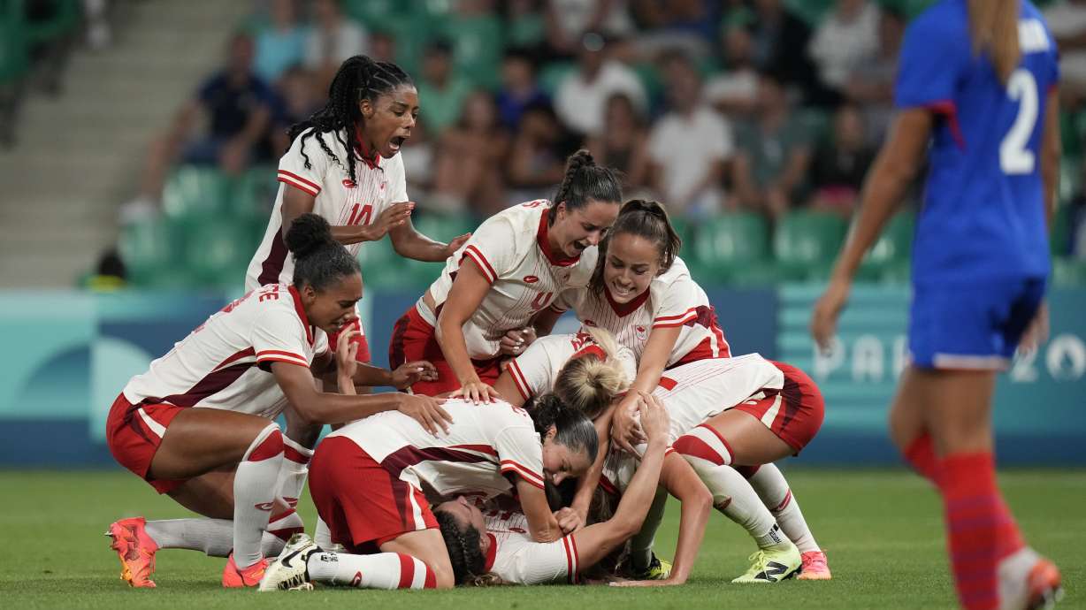 Canada's players celebrate after Vanessa Gille, bottom center, scored her side's second goal during the women's Group A soccer match between Canada and France at Geoffroy-Guichard stadium during the 2024 Summer Olympics, Sunday, July 28, 2024, in Saint-Etienne, France.