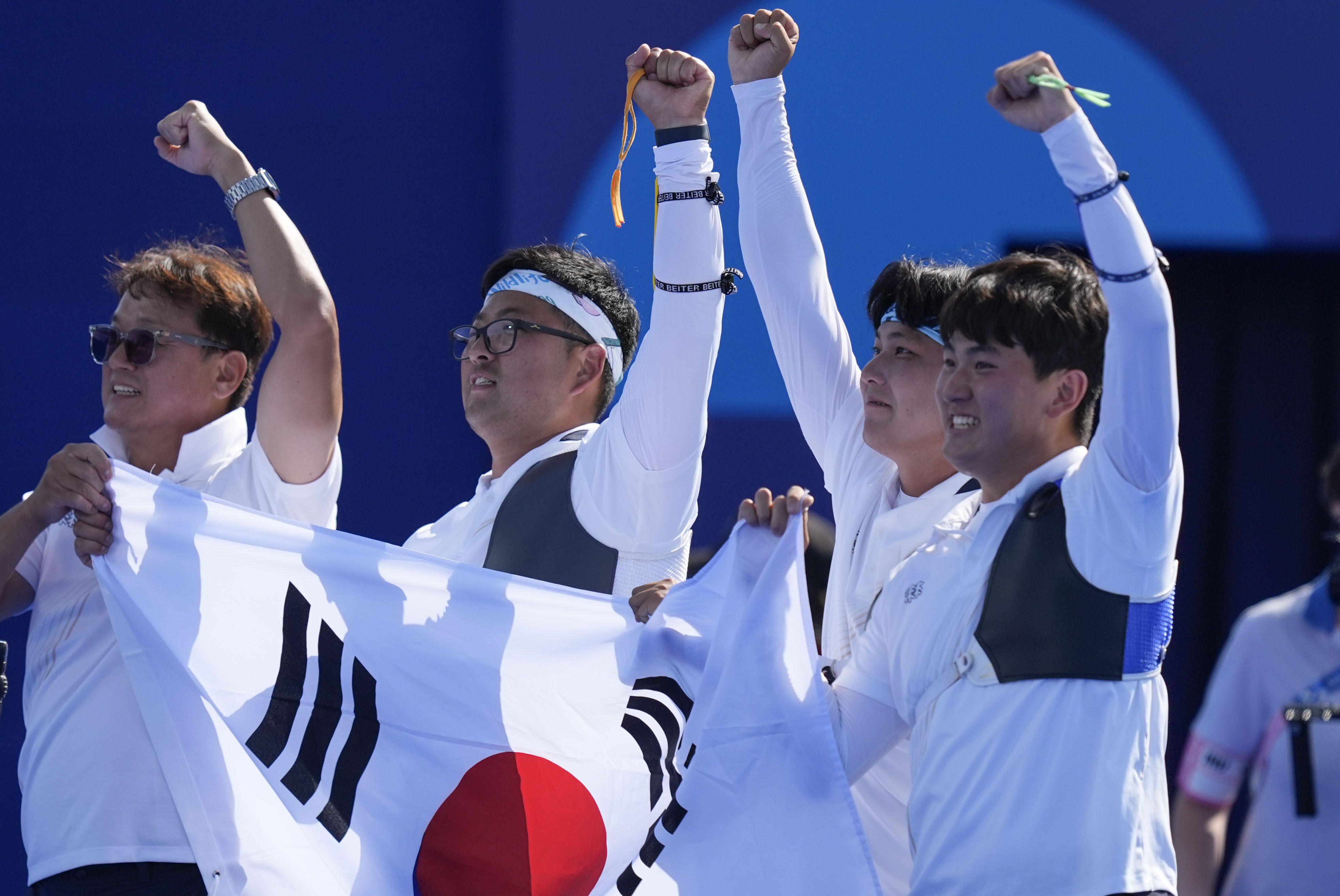 South Korea's Woojin Kim, center, Wooseok Lee, and Je Deok Kim celebrate after a win during the men's team gold medal match Archery competition against France at the 2024 Summer Olympics, Monday, July 29, 2024, in Paris, France.
