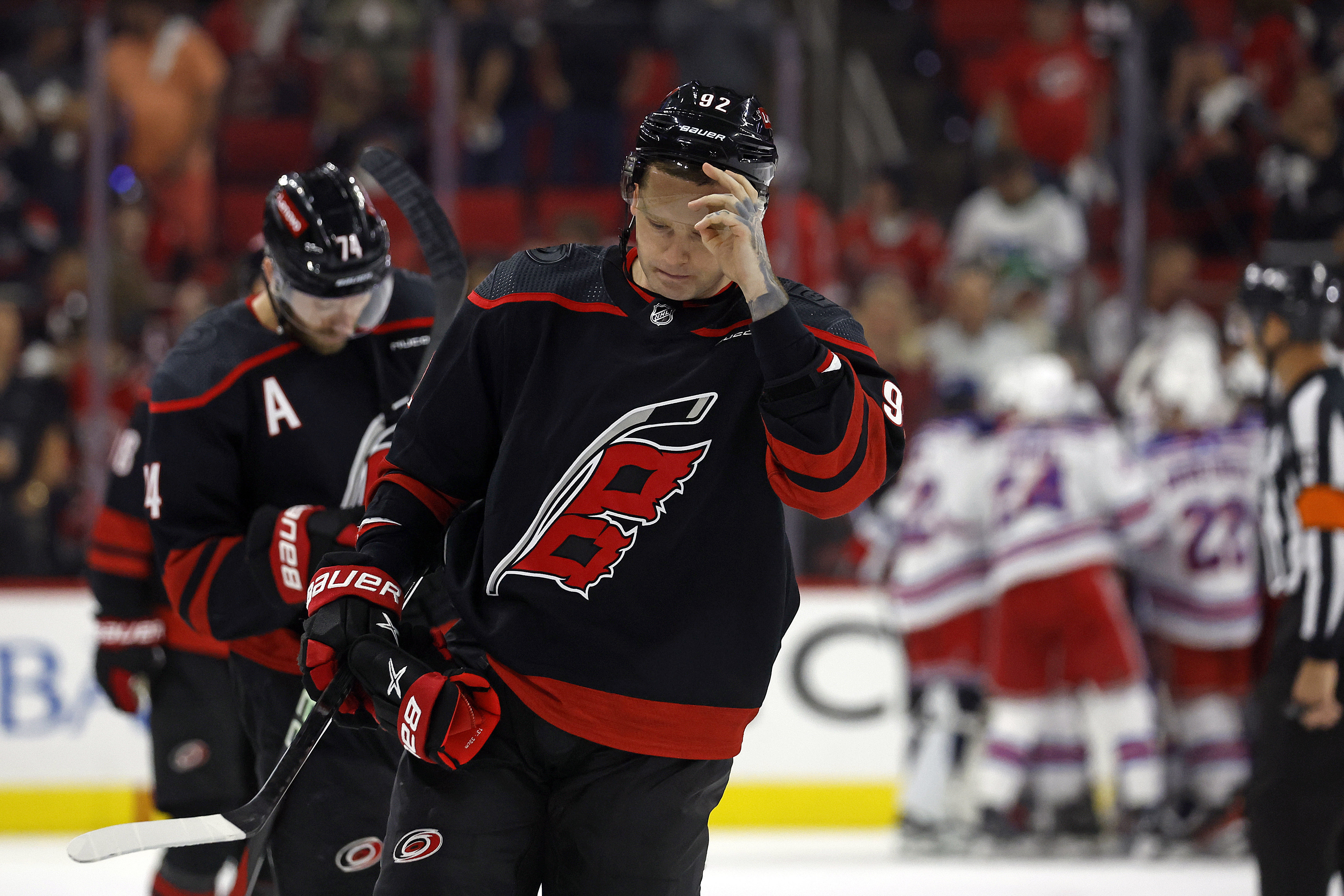 FILE- Carolina Hurricanes' Evgeny Kuznetsov (92) and Jaccob Slavin (74) skate off as New York Rangers celebrate in the background following Game 6 of an NHL hockey Stanley Cup second-round playoff series in Raleigh, N.C., Thursday, May 16, 2024. The Hurricanes have put Kuznetsov on unconditional waivers for the purpose of terminating his NHL contract. General manager Eric Tulsky said the two sides ultimately agreed this was the best course of action for the player and the team. 