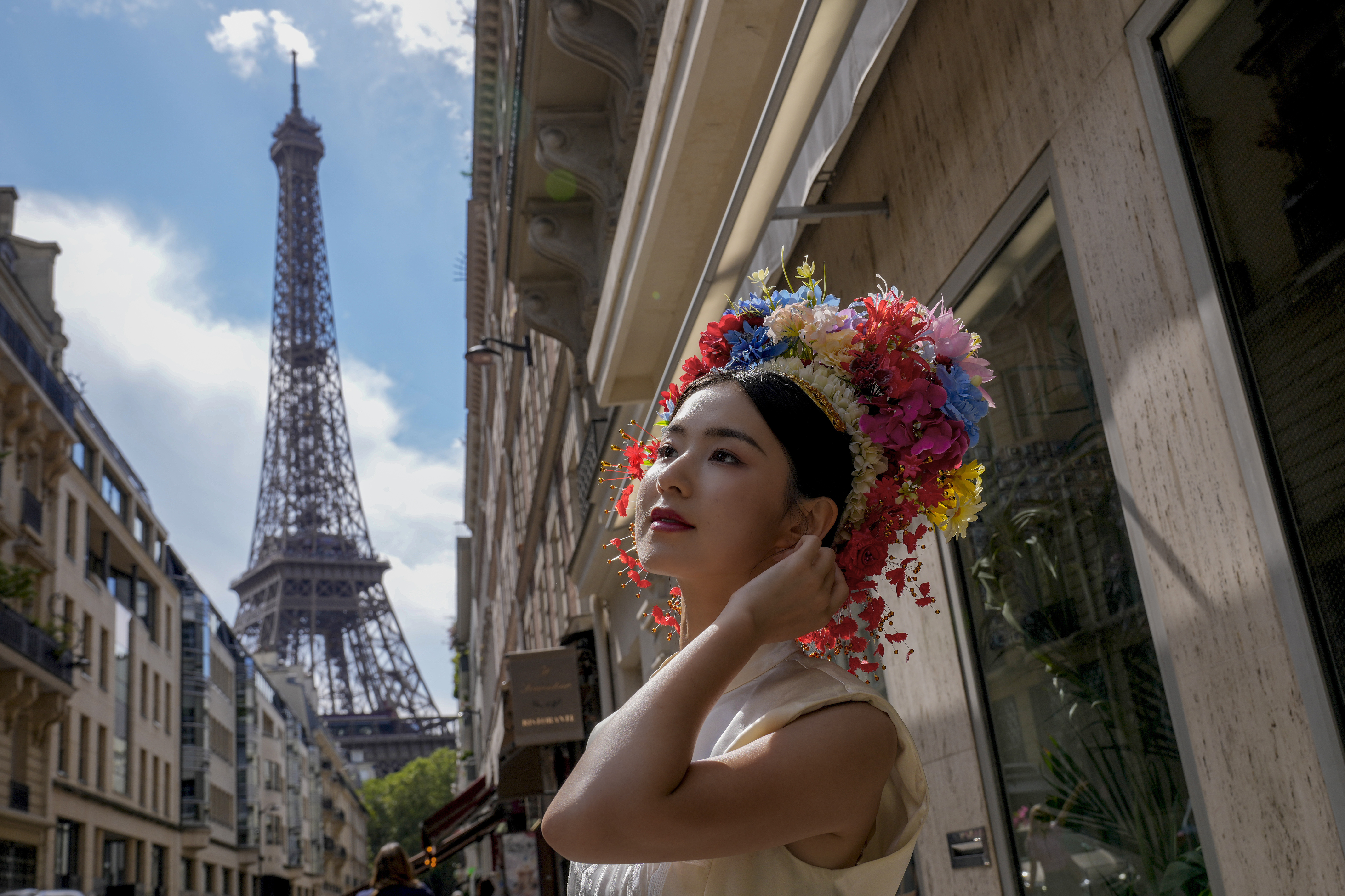 Hu Xiao, from China, poses as her friends take her photograph near the Eiffel Tower at the 2024 Summer Olympics, Sunday, July 28, 2024, in Paris, France. 