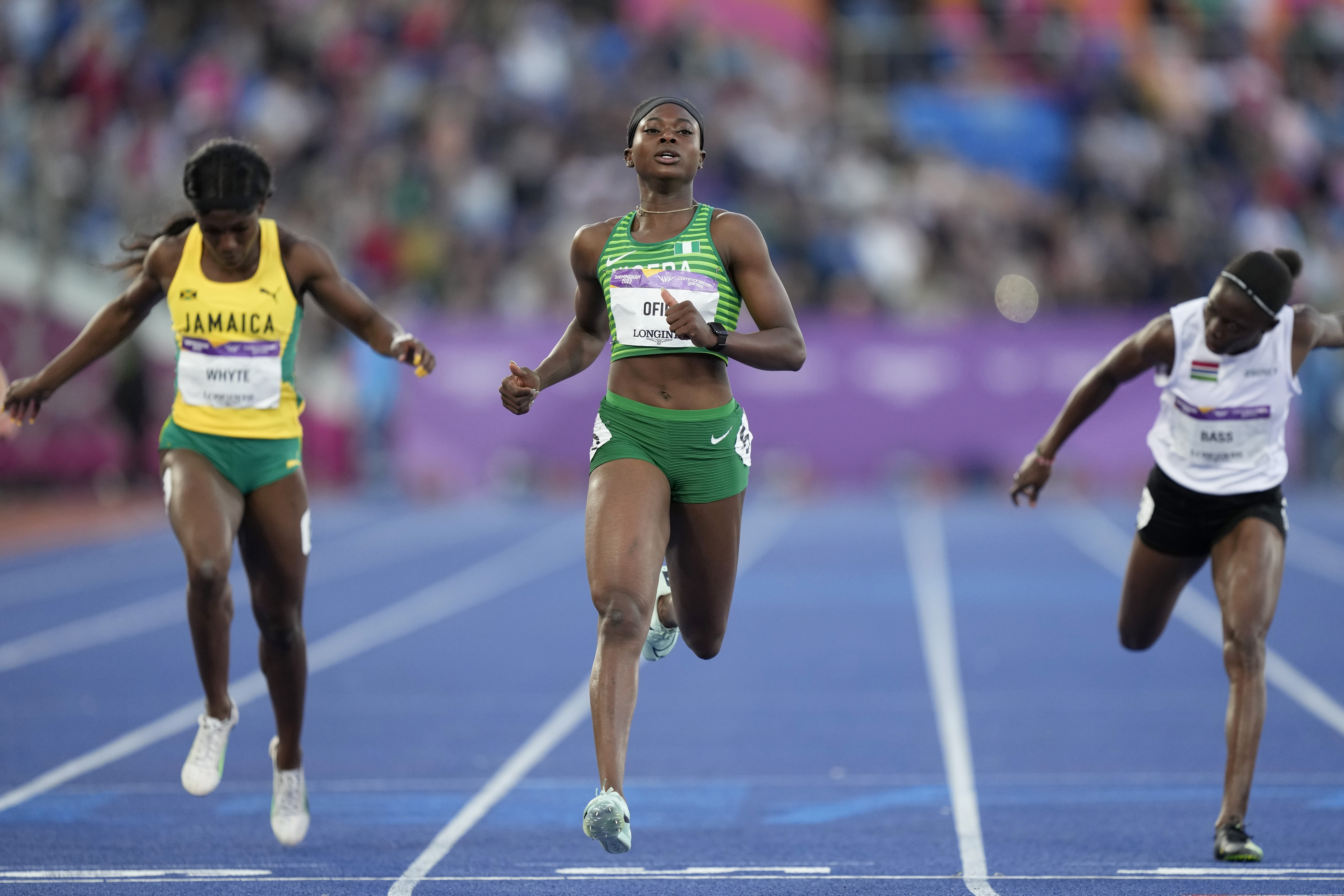 FILE - Favour Ofili of Nigeria, center crosses the finish line ahed of Natalliah Whyte of Jamaica, left, and Gina Bass of The Gambia, right, in a Women's 200 meters semifinal during the athletics competition in the Alexander Stadium at the Commonwealth Games in Birmingham, England, Friday, Aug. 5, 2022. Nigeria's national champion in the women's 100-meter sprint won't run the race at the Olympics because she says her country's track federation didn't enter her into the field in time. 