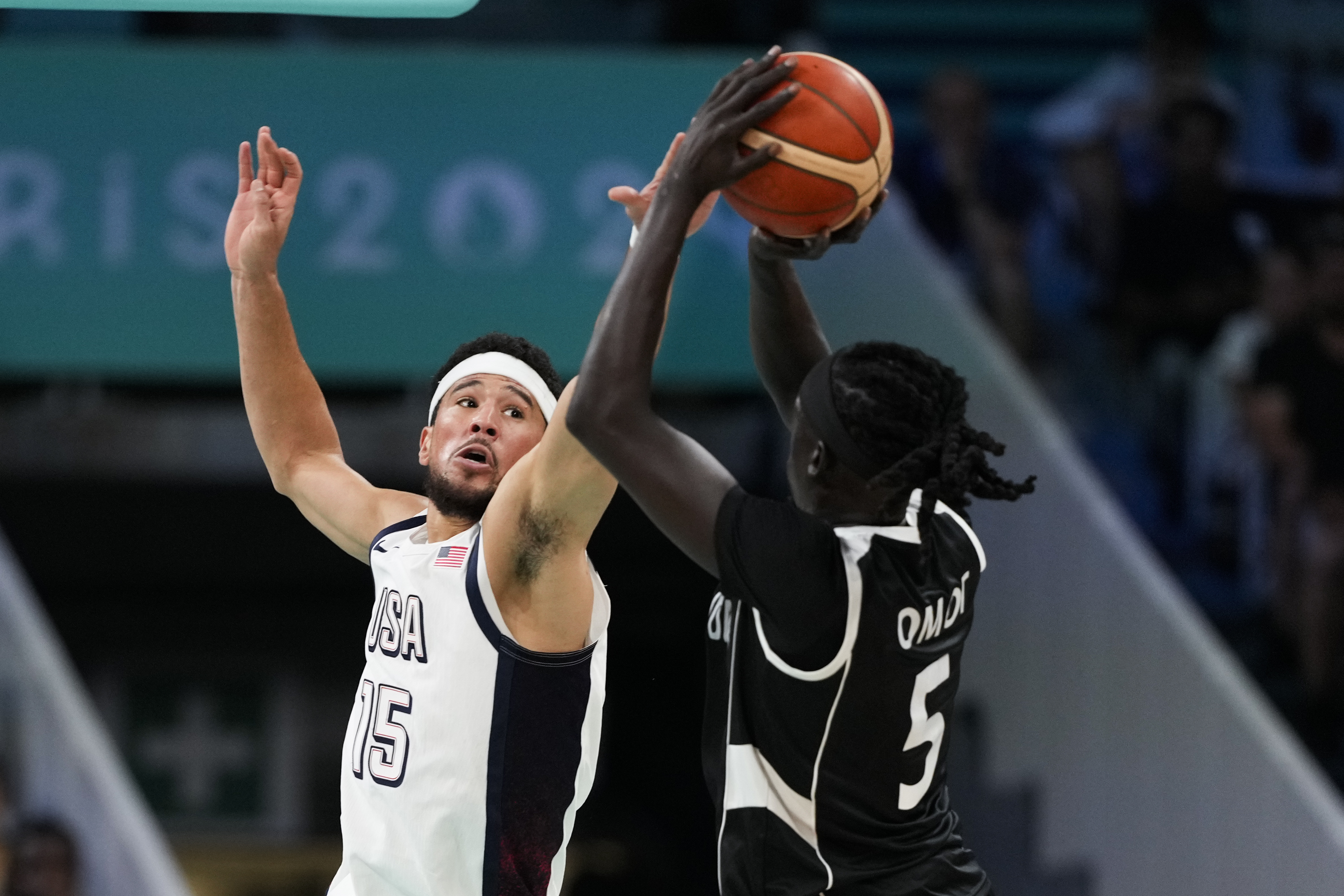 Nuni Omot, of South Sudan, shoots over Devin Booker, of the United States, in a men's basketball game at the 2024 Summer Olympics, Wednesday, July 31, 2024, in Villeneuve-d'Ascq, France. 