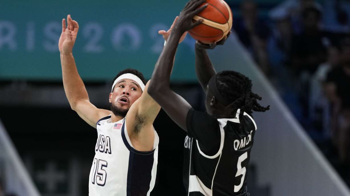 Nuni Omot, of South Sudan, shoots over Devin Booker, of the United States, in a men's basketball game at the 2024 Summer Olympics, Wednesday, July 31, 2024, in Villeneuve-d'Ascq, France.