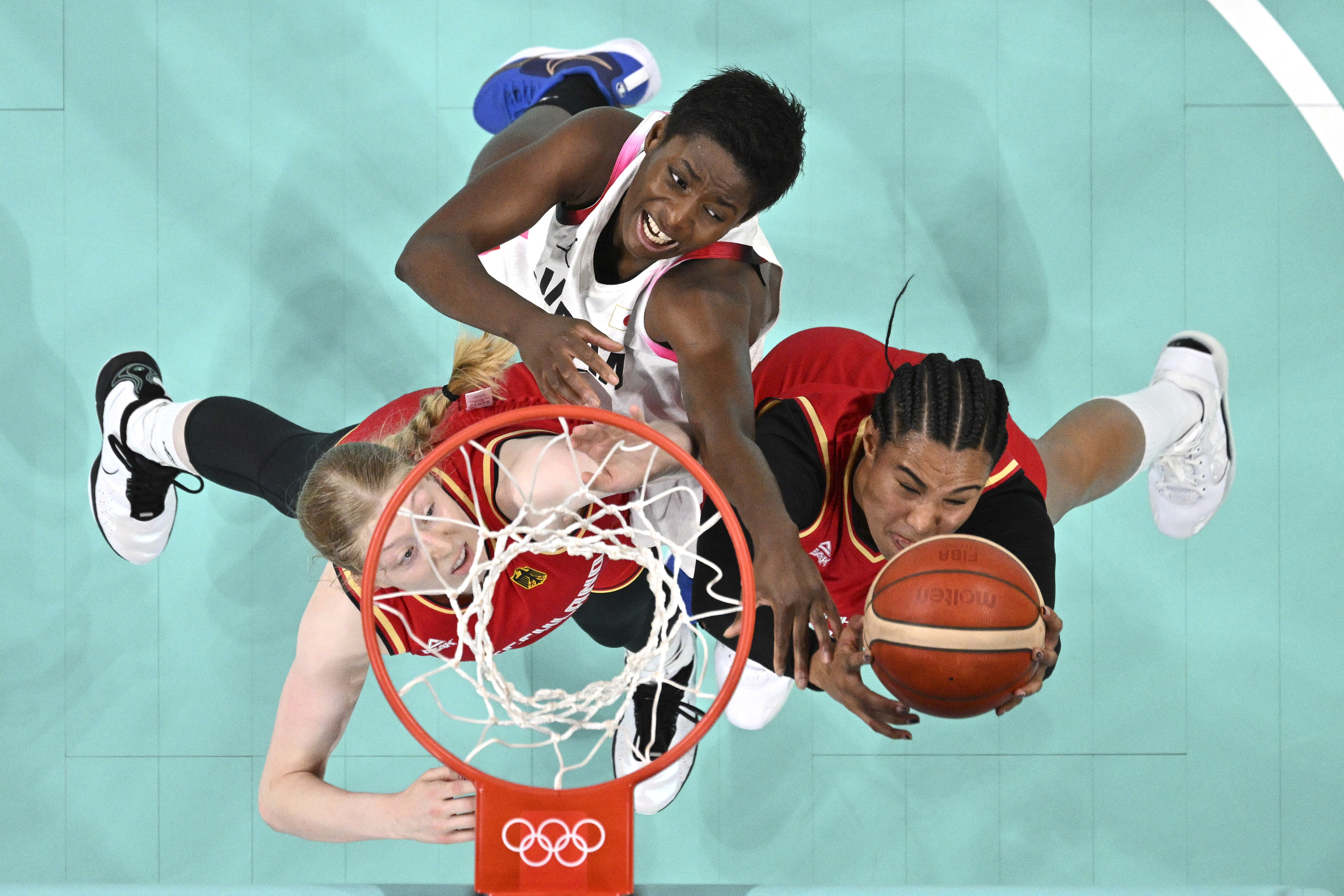 Germany's Frieda Buhner, left, and Germany's Satou Sabally, right, reach for a rebound along with Japan's Evelyn Mawuli in a women's basketball game at the 2024 Summer Olympics, Thursday, Aug. 1, 2024, in Villeneuve-d'Ascq, France. 