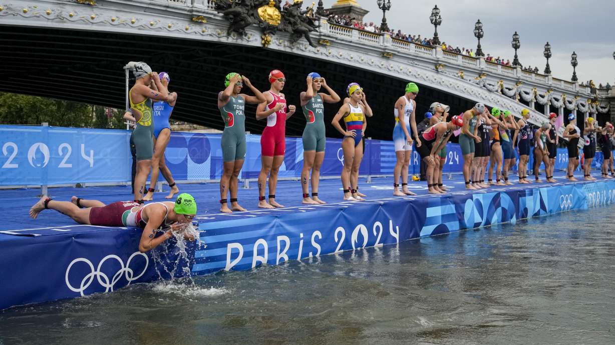 Hungary's Zsanett Kuttor-Bragmayer, left, splashes water on her face before the start of the women's individual triathlon competition at the 2024 Summer Olympics, Wednesday, July 31, 2024, in Paris, France.