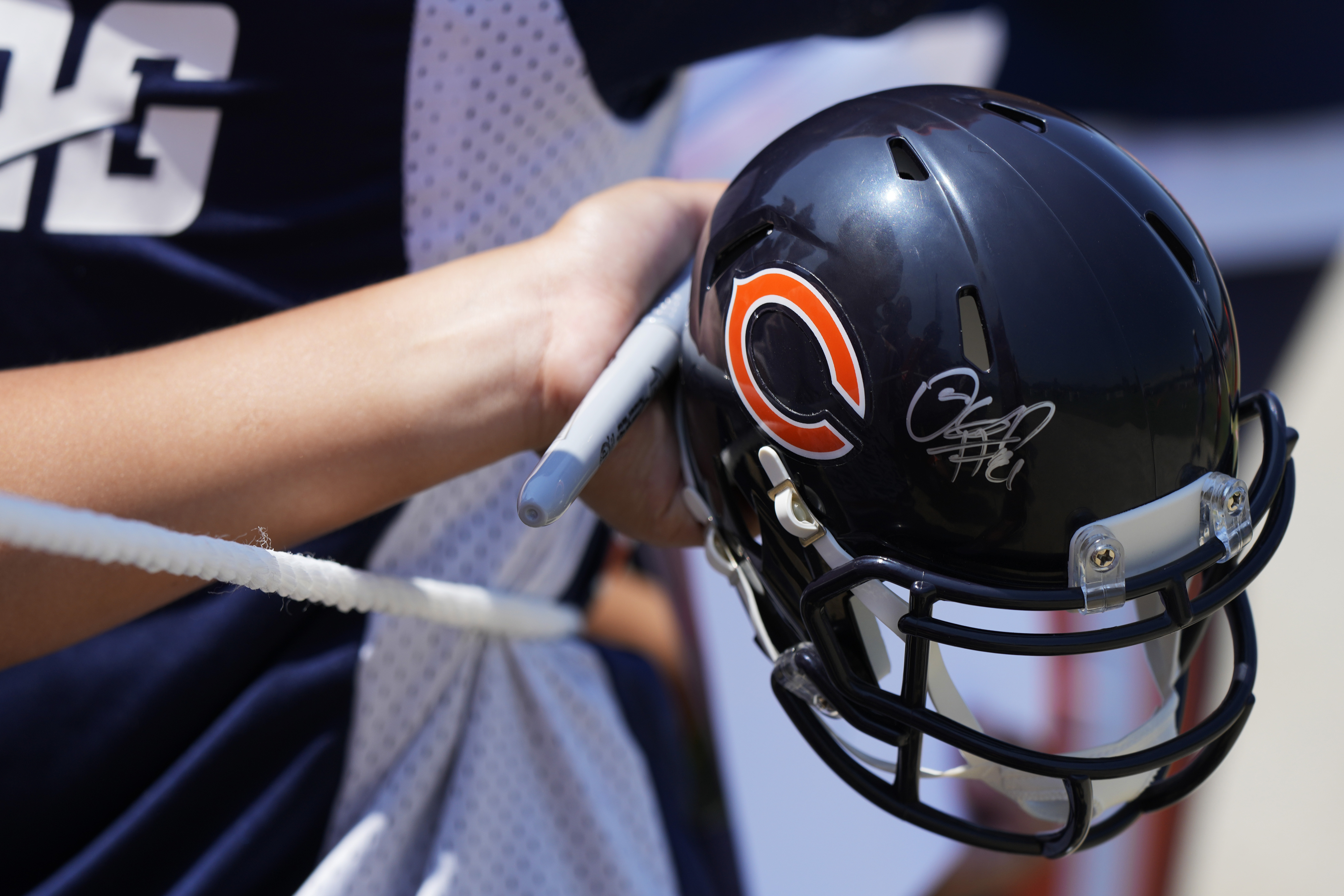 A fan waits with a helmet he hopes to get autographed after Chicago Bears NFL football training camp practice in Lake Forest, Ill., Saturday, July 27, 2024. 