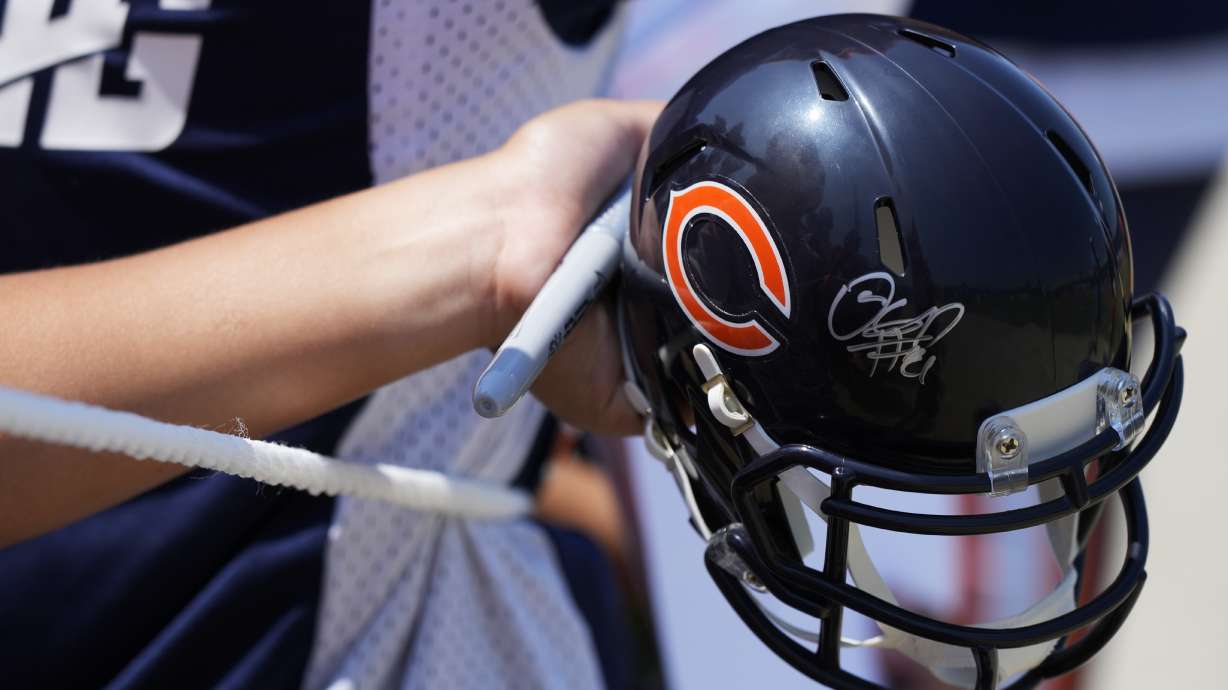 A fan waits with a helmet he hopes to get autographed after Chicago Bears NFL football training camp practice in Lake Forest, Ill., Saturday, July 27, 2024.