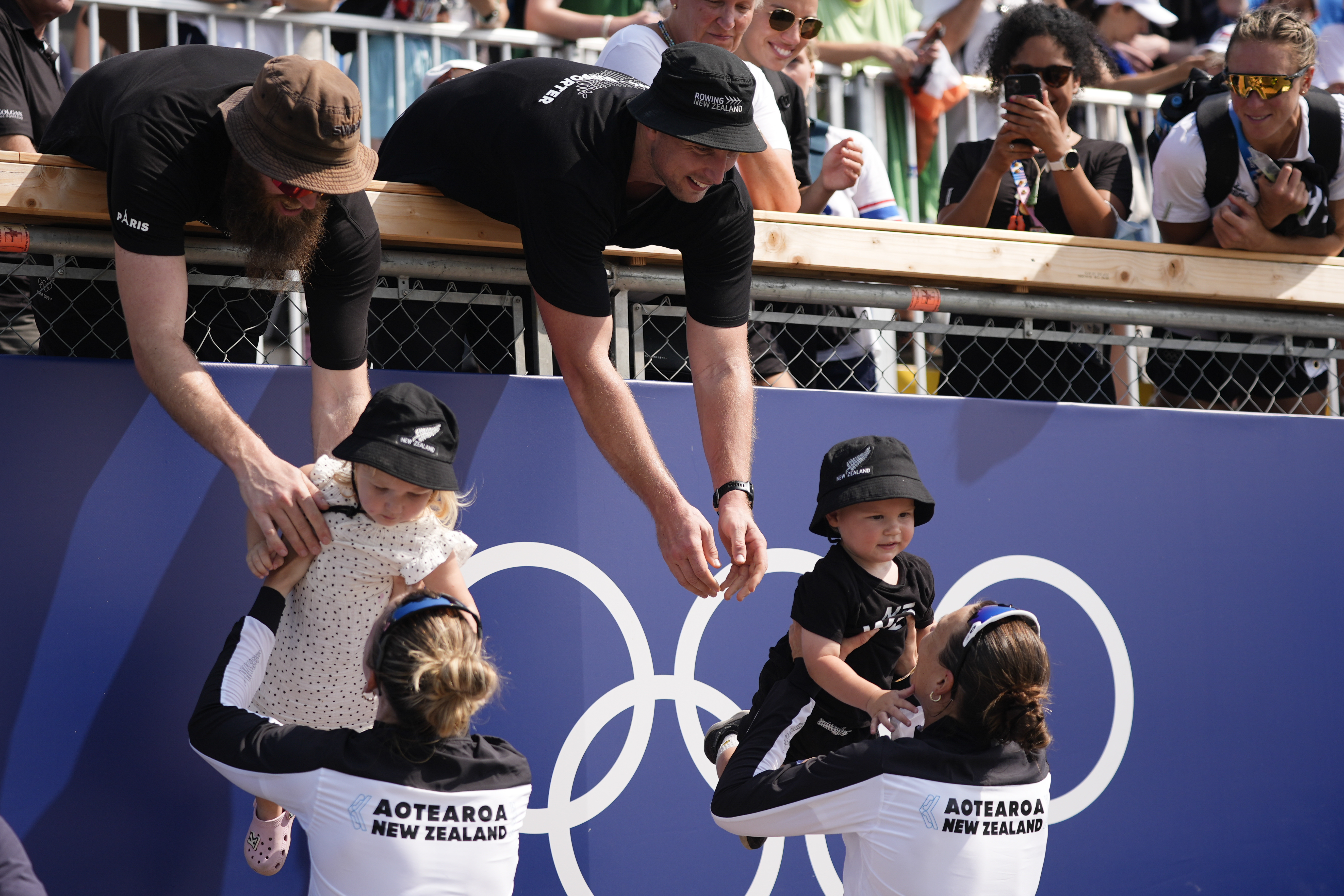 New Zealand's Brooke Francis, left, hands off daughter Keira and Lucy Spoors hands off son Rupert after winning gold in the women's double sculls final at the 2024 Summer Olympics, Thursday, Aug. 1, 2024, in Vaires-sur-Marne, France. 