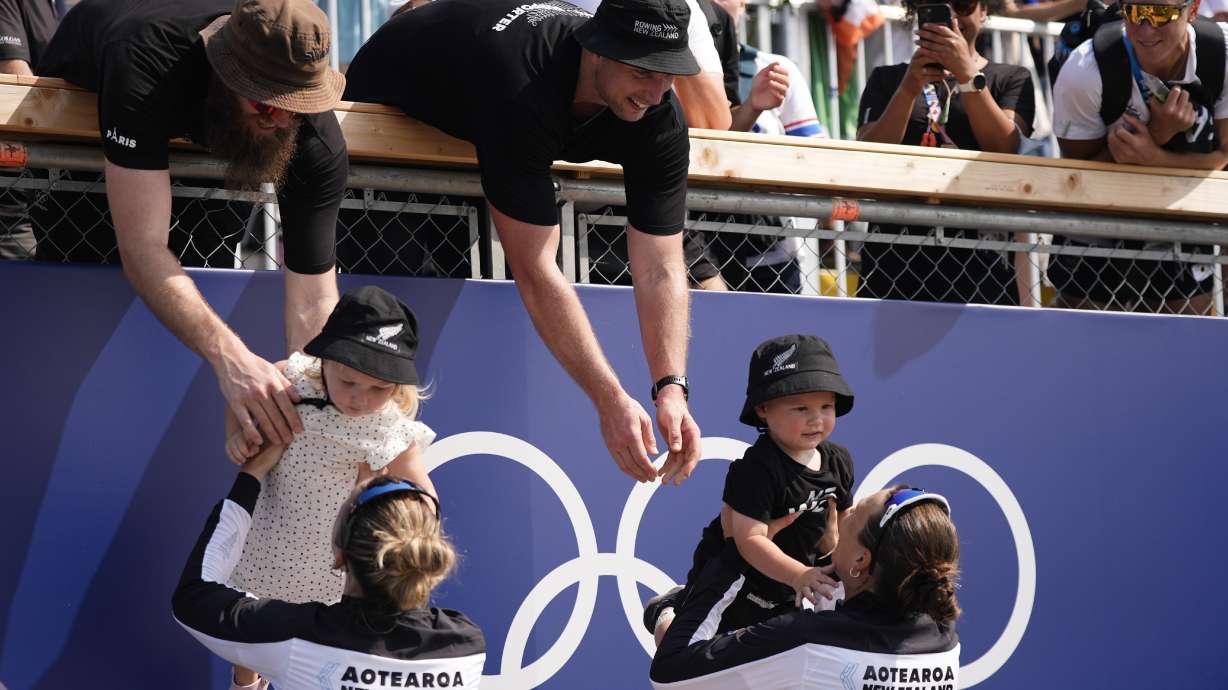 New Zealand's Brooke Francis, left, hands off daughter Keira and Lucy Spoors hands off son Rupert after winning gold in the women's double sculls final at the 2024 Summer Olympics, Thursday, Aug. 1, 2024, in Vaires-sur-Marne, France.
