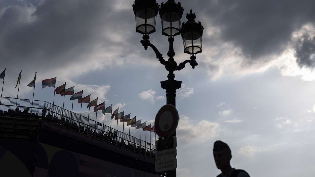 A police officer patrols outside the venue as spectators watch a 3x3 basketball game from the stands at the 2024 Summer Olympics, Thursday, Aug. 1, 2024, in Paris, France.