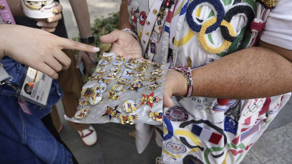 Vivianne Robinson lets a passer by choose one of the pins Robinson collected from USA Olympics 1984, during 2024 Summer Olympics, in Paris, France, Tuesday, July 30, 2024. The Olympics superfan has attended seven Games over the span of 40 years.