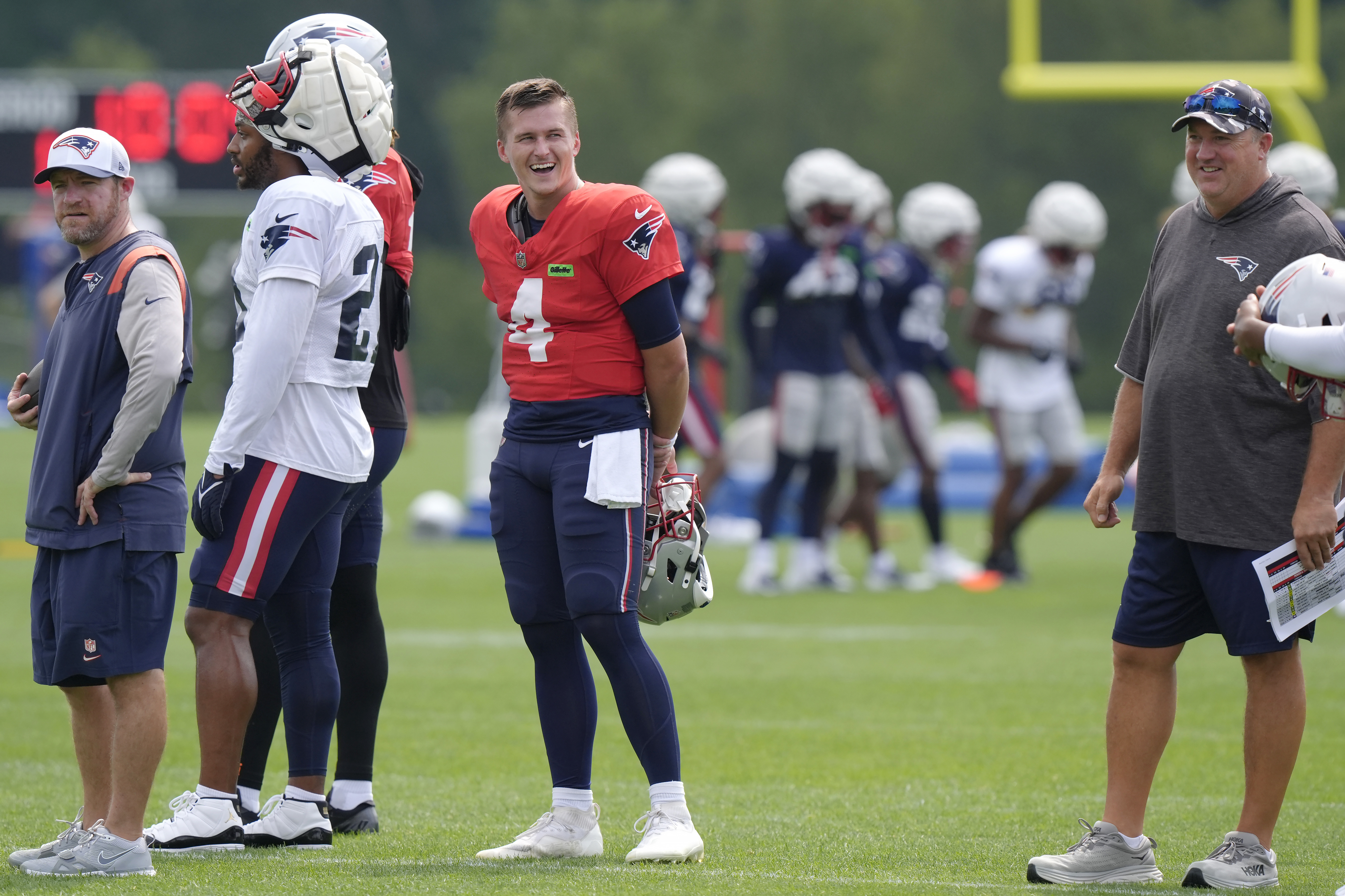 New England Patriots quarterback Bailey Zappe (4) smiles while standing near offensive coordinator Alex Van Pelt, right, during NFL football training camp, Tuesday, July 30, 2024, in Foxborough, Mass.