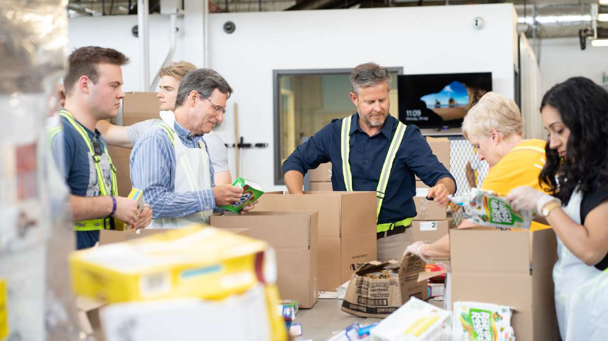 Daily Bread Food Bank CEO Neil Heatherington, center, sorts food alongside Stephen Harvey, second from left, and others Monday to recognize a contribution from The Church of Jesus Christ of Latter-day Saints to support food security in Toronto.