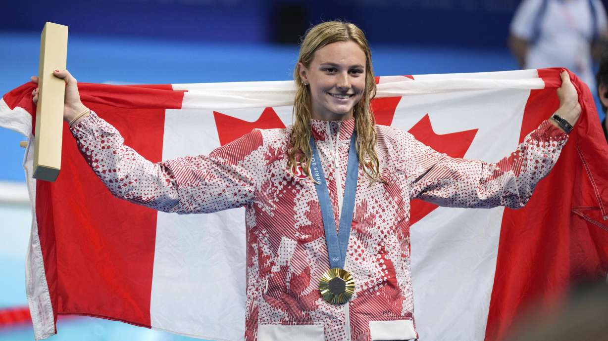Summer McIntosh, of Canada, celebrates with the gold medal during the awards ceremony for the women's 200-meter butterfly at the 2024 Summer Olympics in Nanterre, France, Thursday, Aug. 1, 2024.