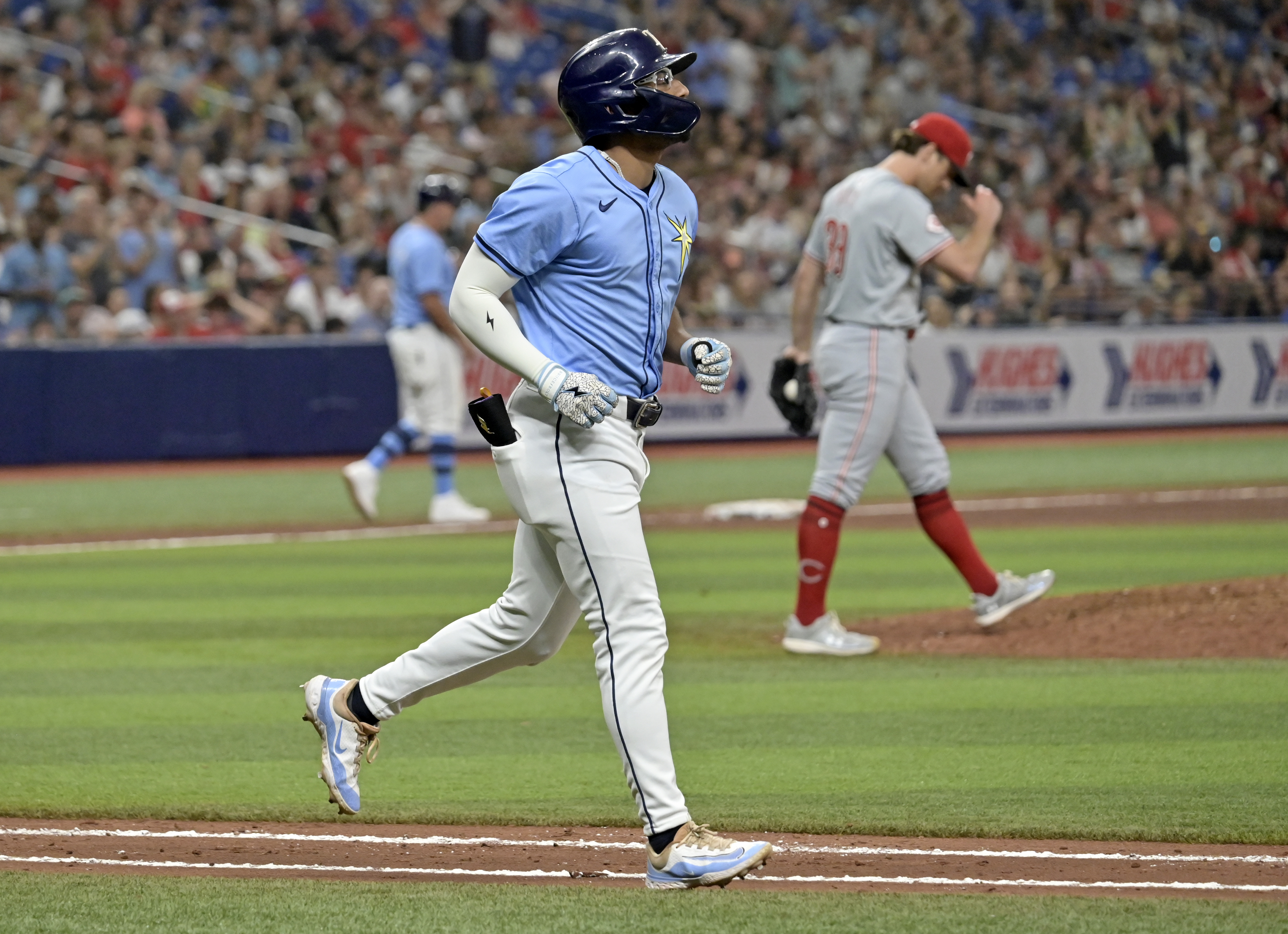 Tampa Bay Rays' Richie Palacios jogs to first base after walking in the go-ahead run from Cincinnati Reds reliever Lucas Sims, right, during the eighth inning of a baseball game, Sunday, July 28, 2024, in St. Petersburg, Fla.