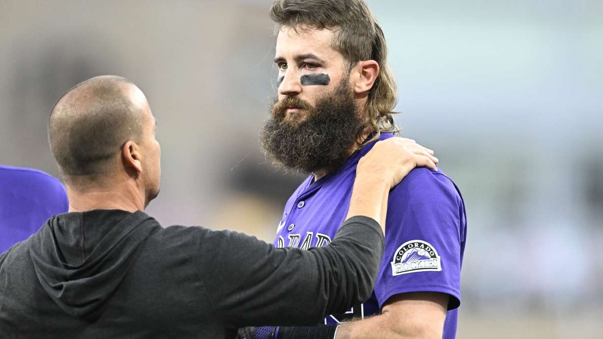 An unidentified trainer, left, looks at Colorado Rockies' Charlie Blackmon, right, after Blackmon was hit with a throw during the third inning of a baseball game against the San Diego Padres, Friday, Aug. 2, 2024, in San Diego.