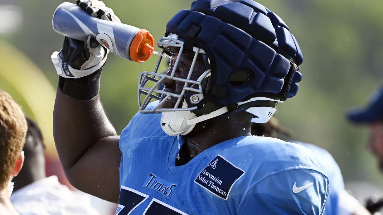 Tennessee Titans offensive lineman Nicholas Petit-Frere squirts his face with water after a blocking drill during an NFL football training camp practice Saturday, Aug. 3, 2024, in Nashville, Tenn.