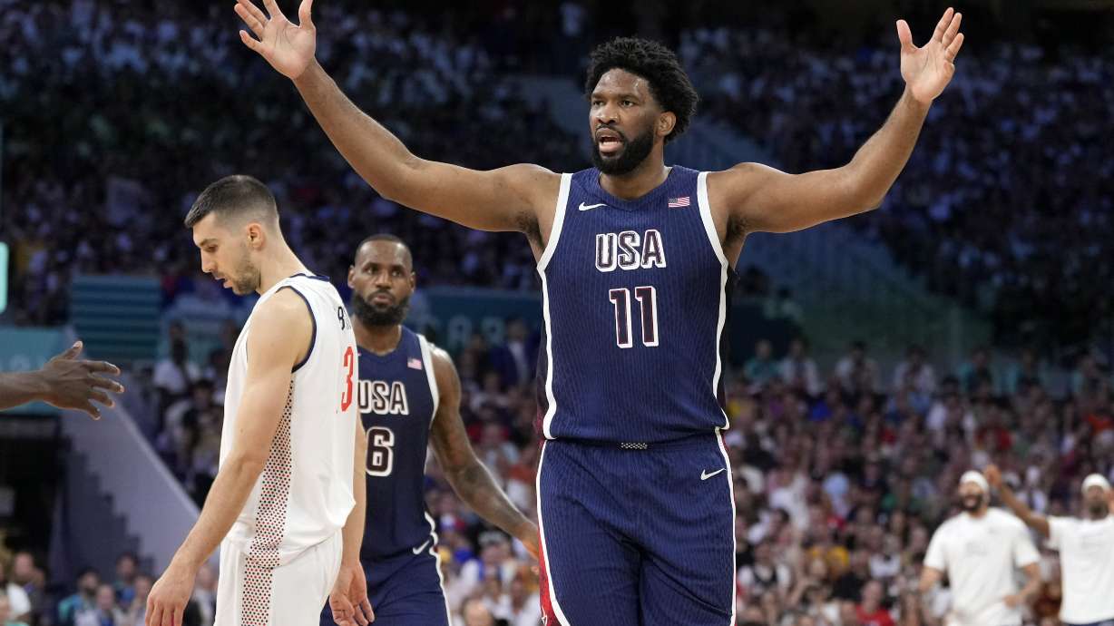 Joel Embiid, right, of the United States, reacts after scoring and being fouled as Filip Petrusev, of Serbia, walks away in a men's basketball game at the 2024 Summer Olympics, Sunday, July 28, 2024, in Villeneuve-d'Ascq, France.