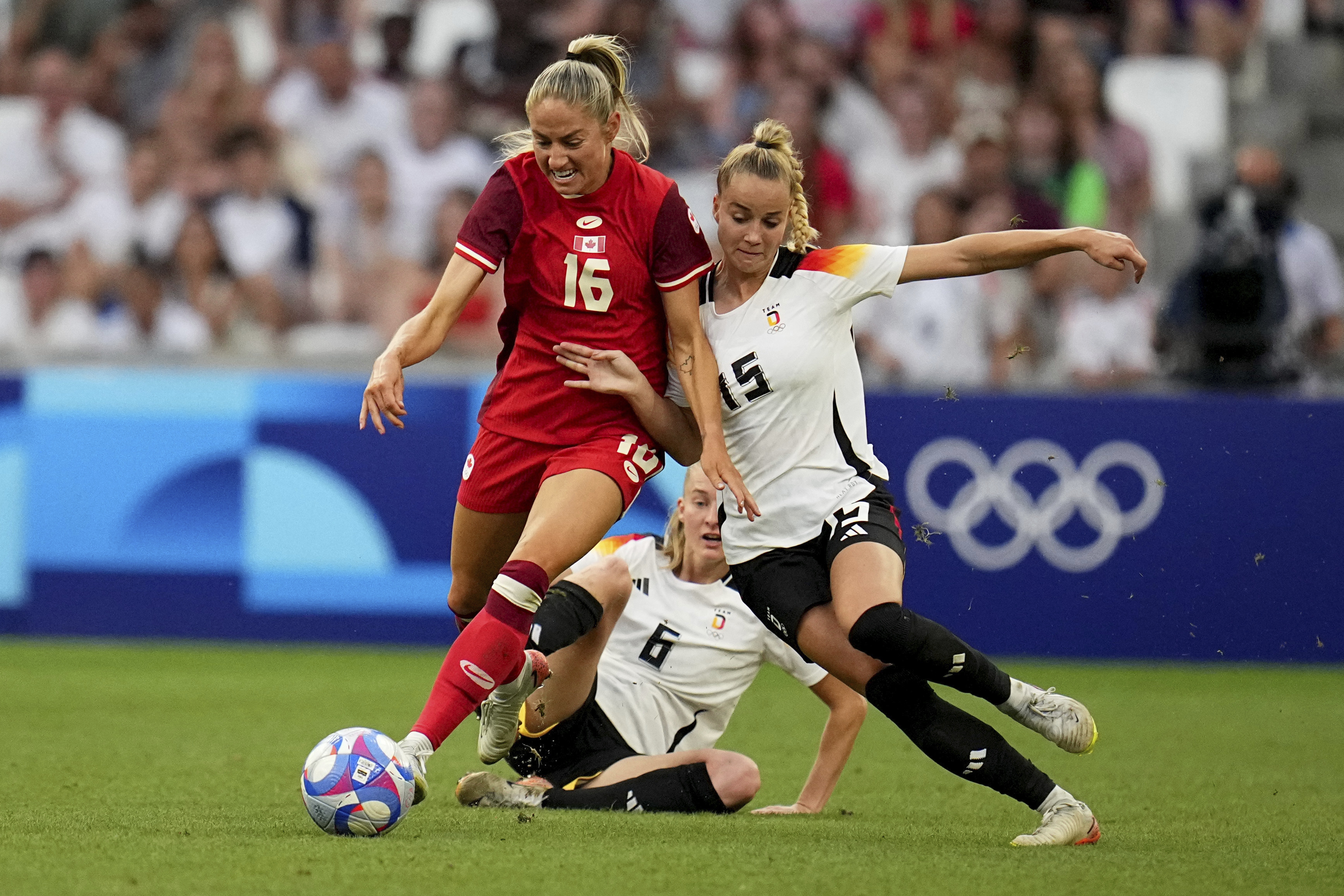 Canada's Janine Beckie fights for the ball with Germany's Giulia Gwinn and Janina Minge during a women's quarterfinal soccer match between Canada and Germany at the 2024 Summer Olympics, Saturday, Aug. 3, 2024, at Marseille Stadium in Marseille, France. 