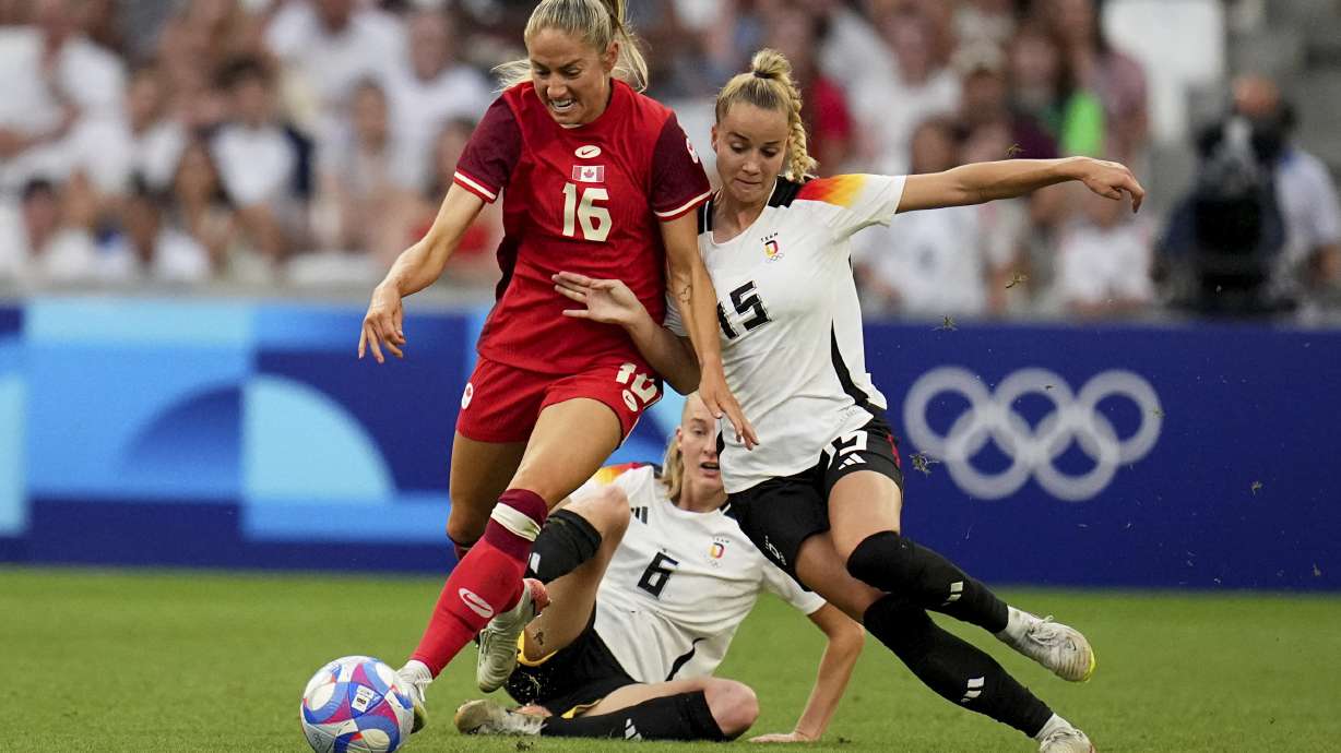 Canada's Janine Beckie fights for the ball with Germany's Giulia Gwinn and Janina Minge during a women's quarterfinal soccer match between Canada and Germany at the 2024 Summer Olympics, Saturday, Aug. 3, 2024, at Marseille Stadium in Marseille, France.