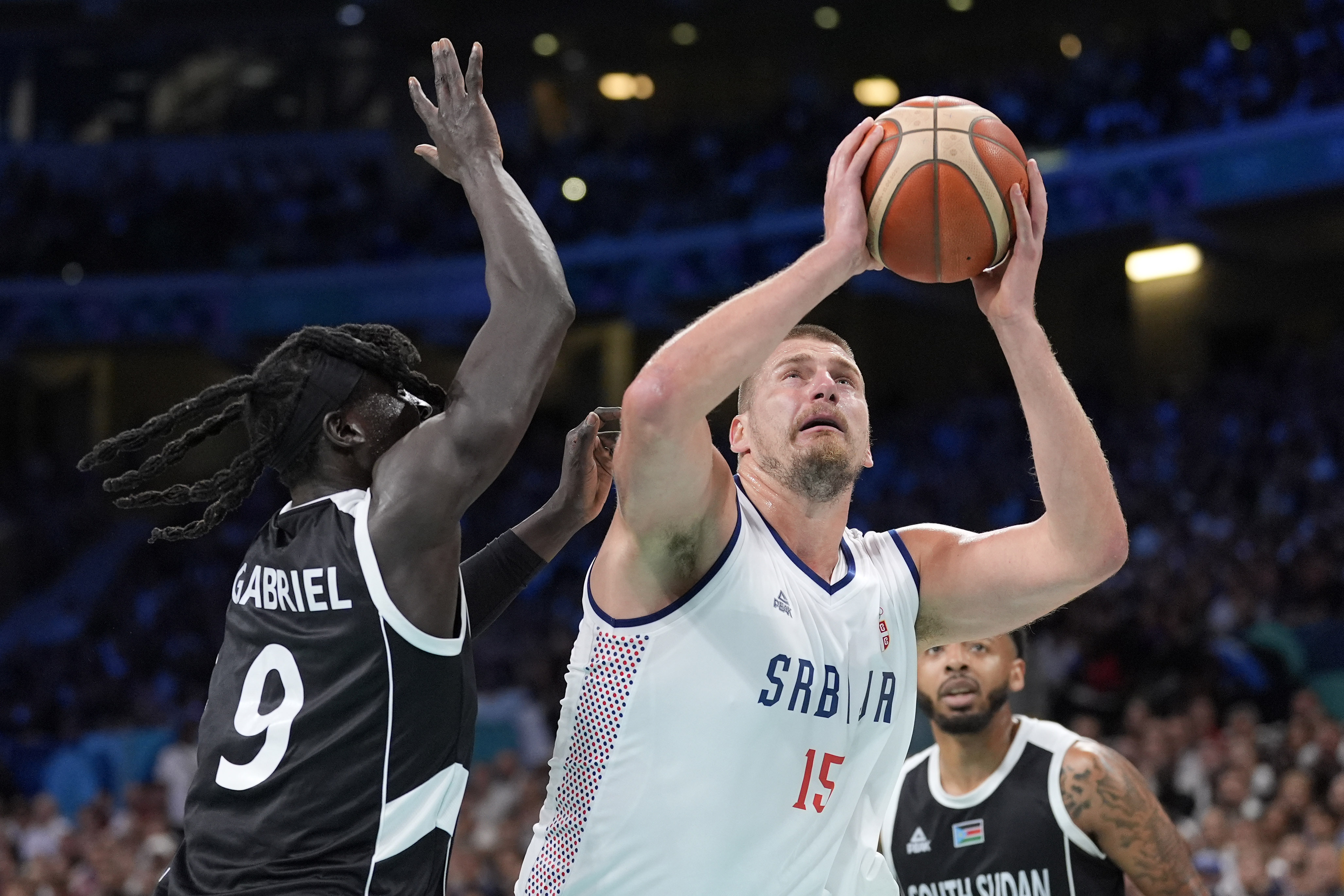 Serbia's Nikola Jokic, center, shoots as South Sudan's Wenyen Gabriel, left, defends during a men's basketball game at the 2024 Summer Olympics, Saturday, Aug. 3, 2024, in Villeneuve-d'Ascq, France.