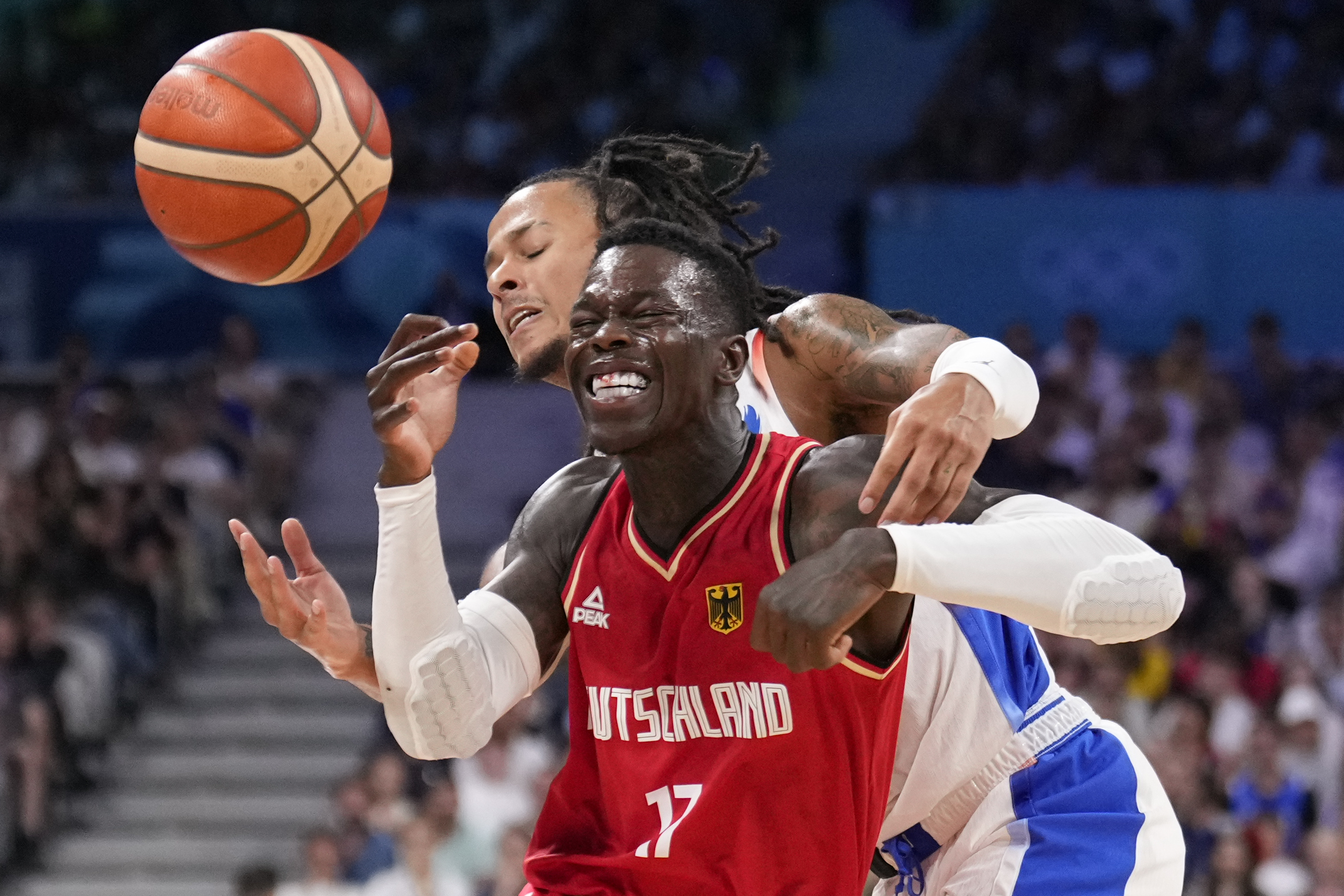 Dennis Schroder, of Germany, is hit as he drives past Matthew Strazel, of France, in a men's basketball game at the 2024 Summer Olympics, Friday, Aug. 2, 2024, in Villeneuve-d'Ascq, France. 