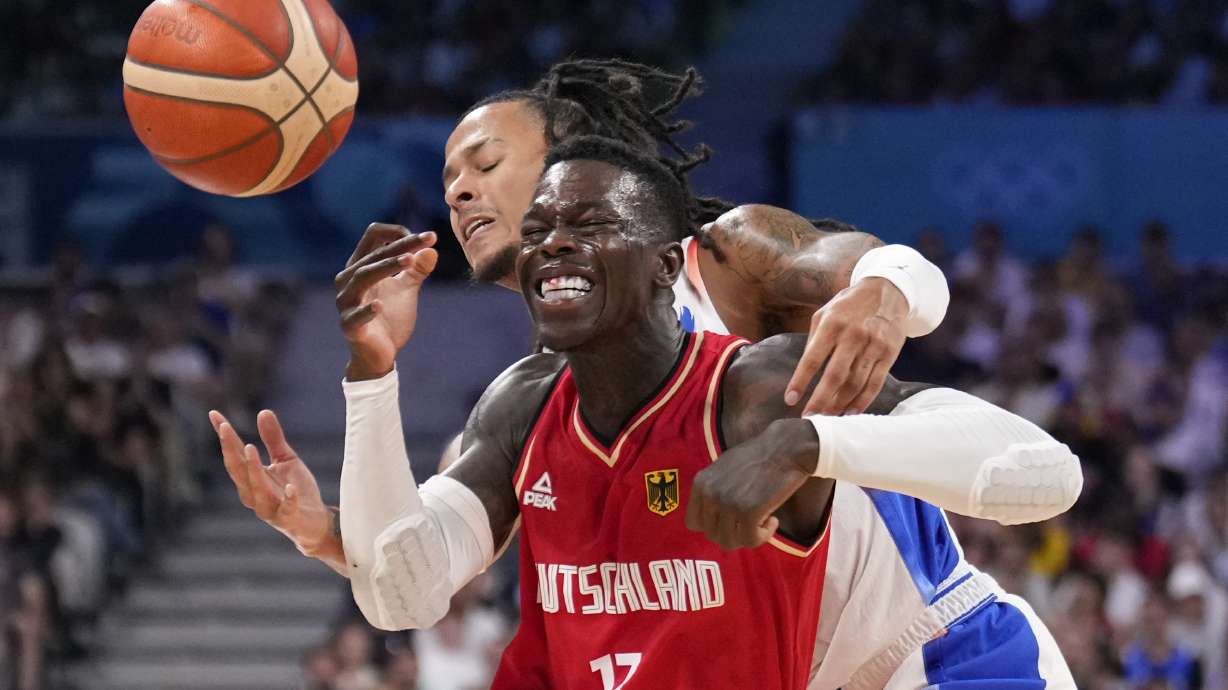 Dennis Schroder, of Germany, is hit as he drives past Matthew Strazel, of France, in a men's basketball game at the 2024 Summer Olympics, Friday, Aug. 2, 2024, in Villeneuve-d'Ascq, France.