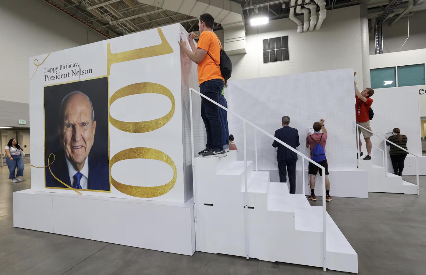 People sign a giant birthday card for President Russell M. Nelson’s upcoming 100th birthday at the 2024 Utah Area Young Single Adult Conference at the Salt Palace Convention Center in Salt Lake City on Friday.