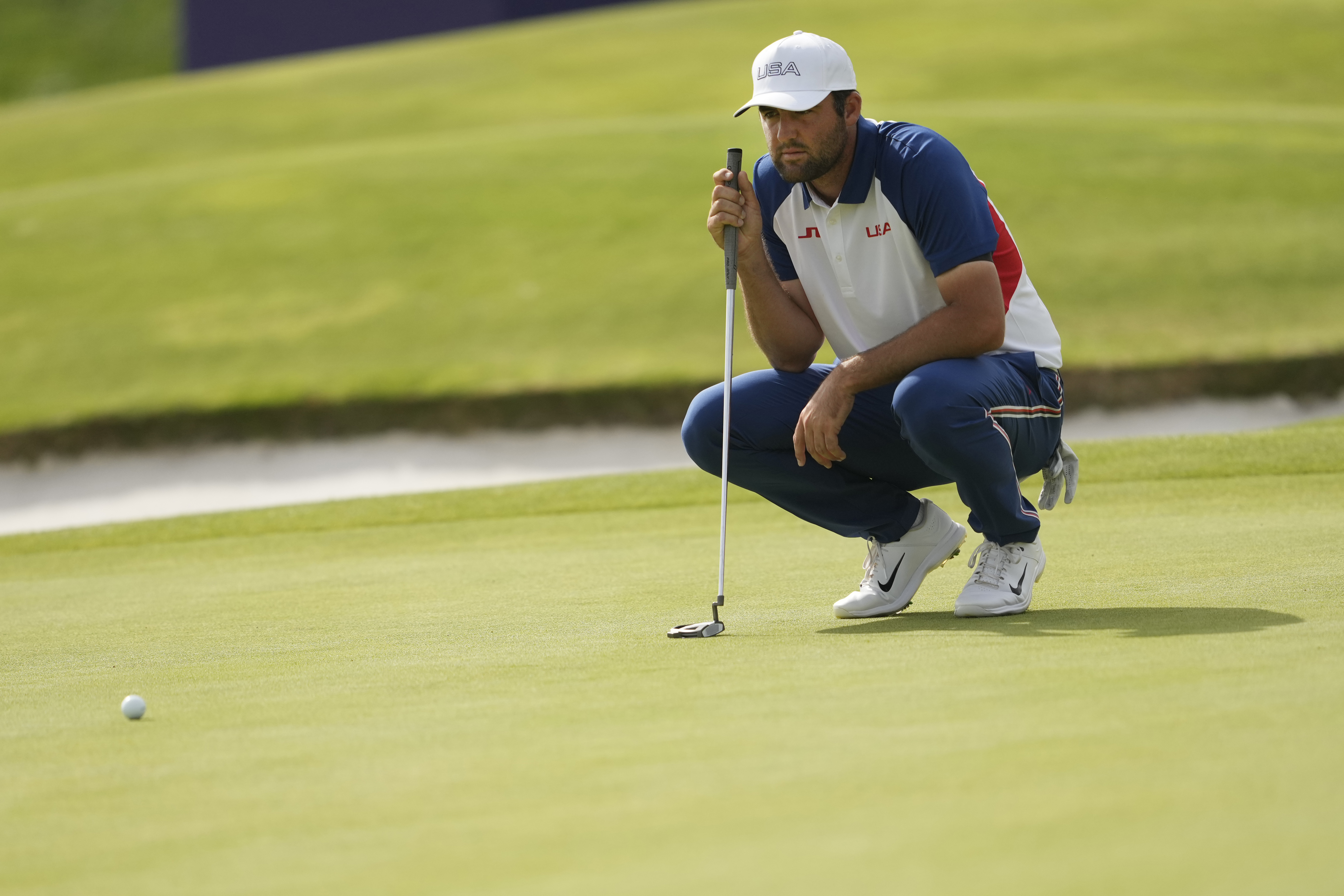 Scottie Scheffler, of the United States, looks at the lie of his putt on the 18th green during the final round of the men's golf at the 2024 Summer Olympics, Sunday, Aug. 4, 2024, at Le Golf National in Saint-Quentin-en-Yvelines, France. 