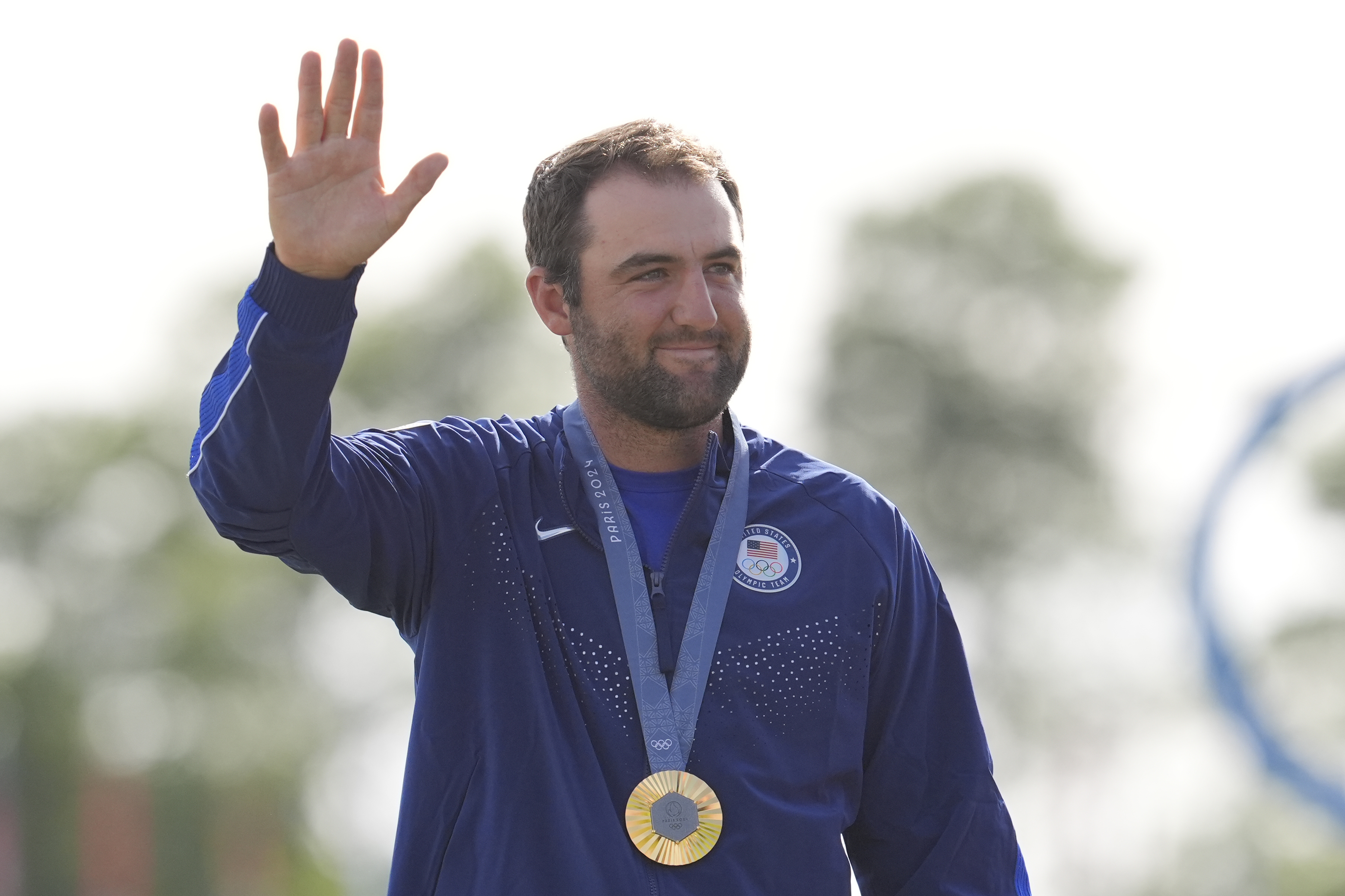 Scottie Scheffler, of the United States, waves to the crowd with his gold medal for men's golf during the medal ceremony at the 2024 Summer Olympics, Sunday, Aug. 4, 2024, at Le Golf National in Saint-Quentin-en-Yvelines, France. Scottie Scheffler, of the United States, won the gold medal with Tommy Fleetwood, of Britain, silver and Hideki Matsuyama, of Japan, the bronze.