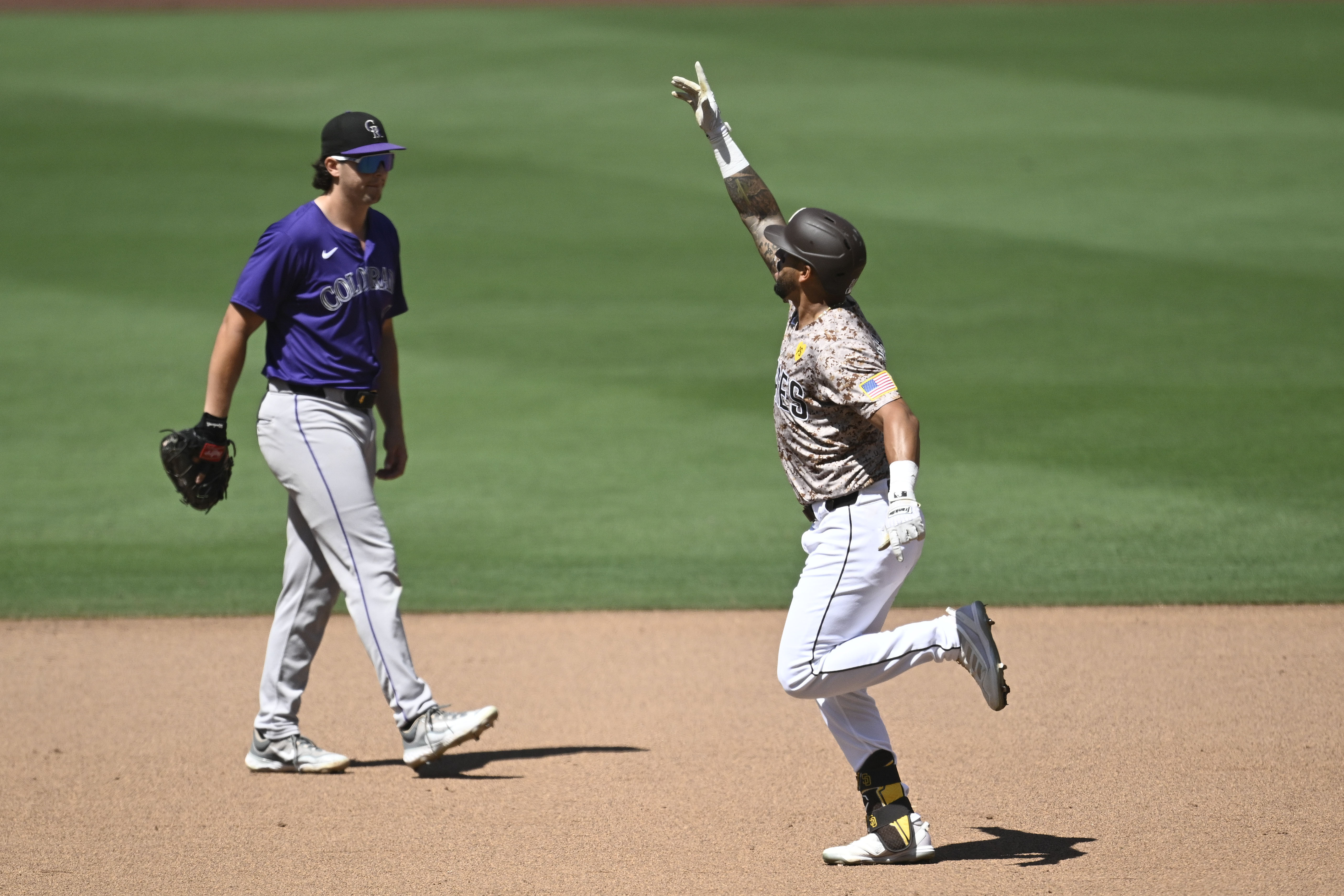 San Diego Padres' David Peralta, right, celebrates after hitting a three-run home run as Colorado Rockies first baseman Michael Toglia, left, looks on during the seventh inning of a baseball game Sunday, Aug. 4, 2024, in San Diego. 
