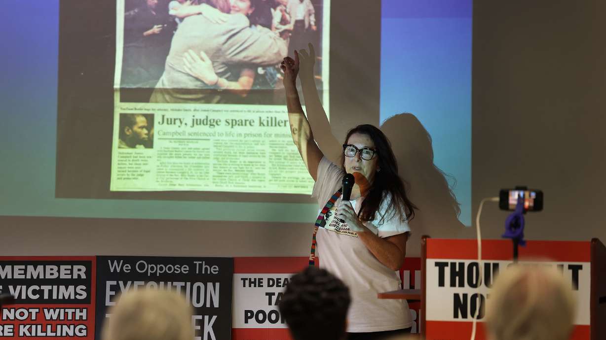 SueZann Bosler shows a news article while speaking about her father's murder and her assault to attendees at Blessed Sacrament Parish Center in Sandy Sunday. She and others are opposed to this week's scheduled execution of Taberon Honie in Utah.