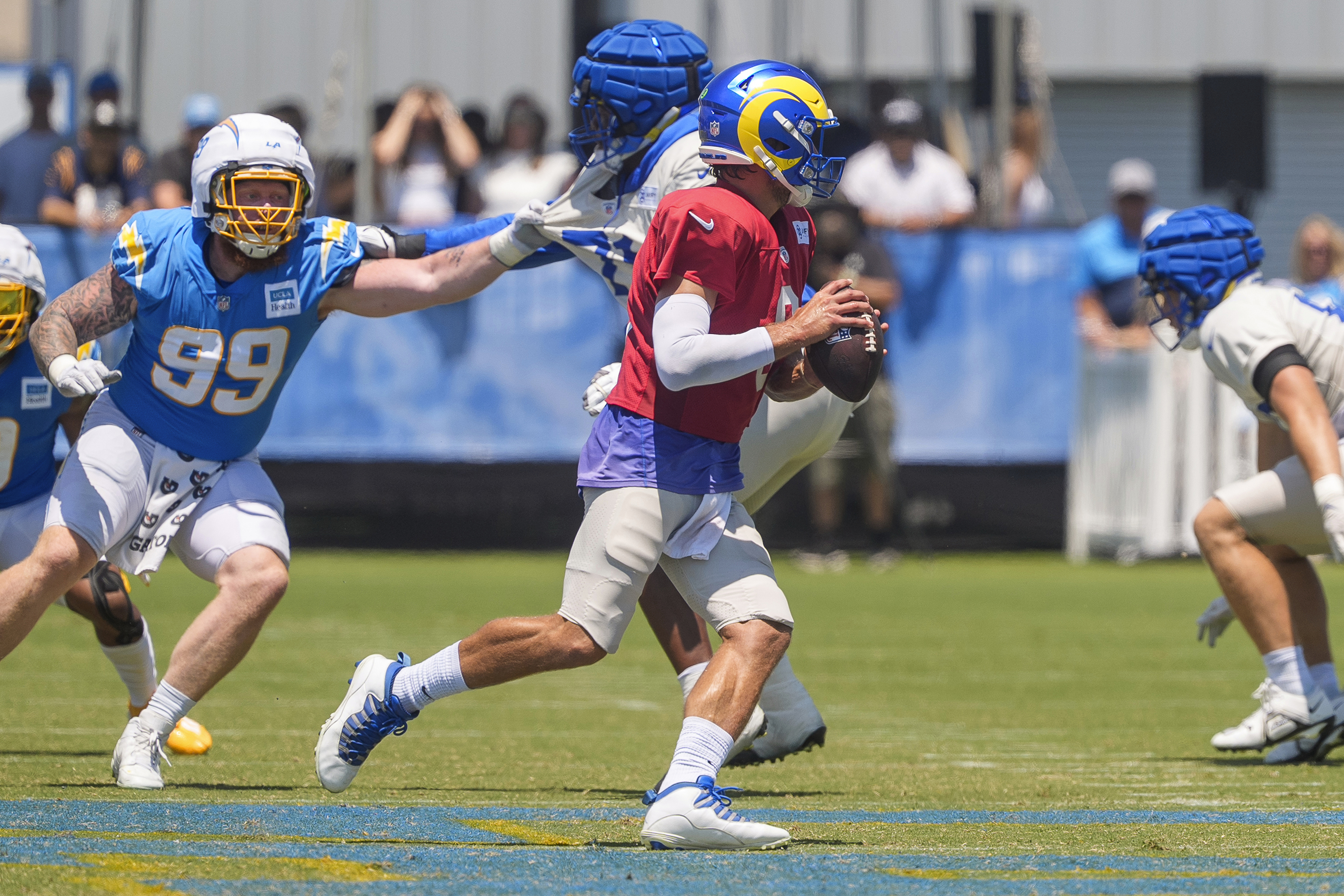 Los Angeles Rams quarterback Matthew Stafford, center front, runs with the ball during NFL football practice at The Bolt in El Segundo, Calif., Sunday, Aug. 4, 2024. Los Angeles Chargers defensive tackle Scott Matlock (99) defends. The Rams and the Chargers are having joint practices.
