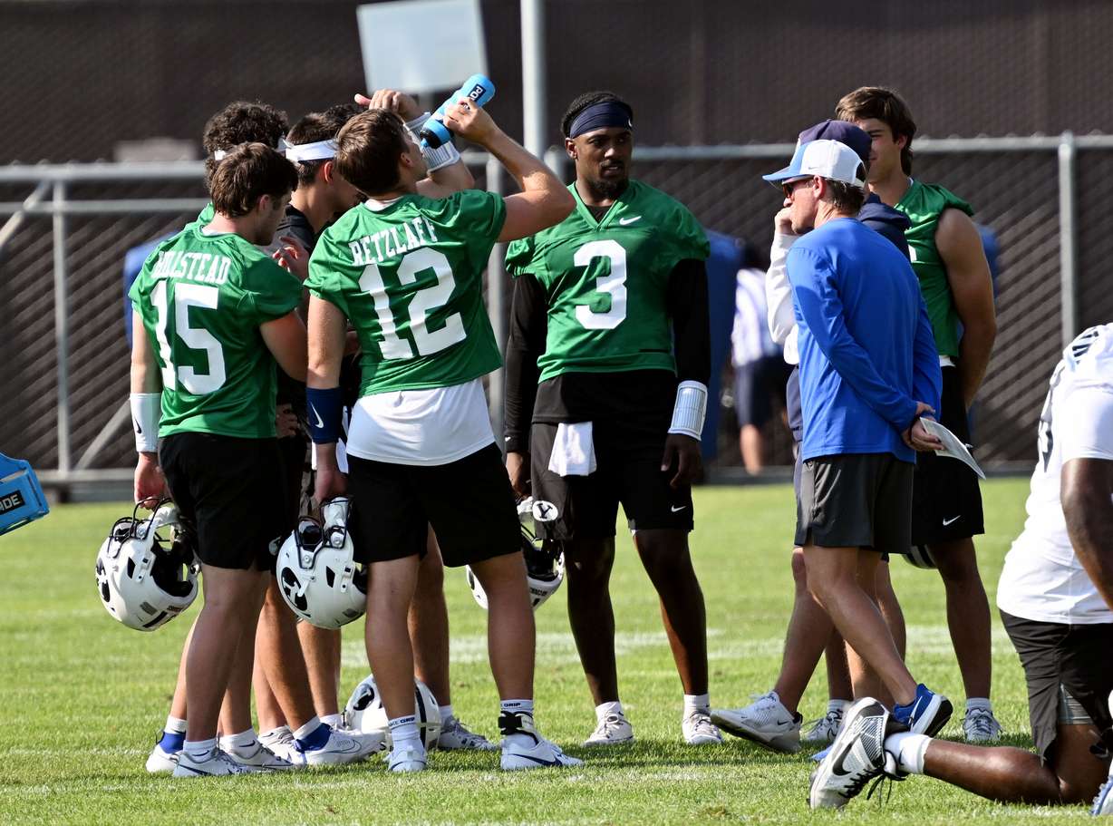 BYU quarterbacks, led by McCae Hillstead (15), Jake Retzlaff (12) and Gerry Bohanon Jr. (3) huddle with offensive coordinator Aaron Roderick as BYU completes their first fall football practice in Provo, Wednesday, July 31, 2024.