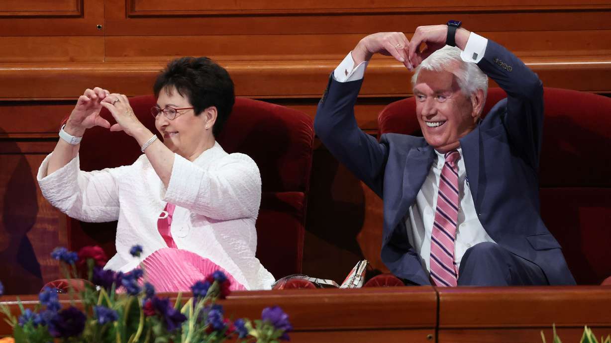 Elder Dieter F. Uchtdorf of the Quorum of the Twelve Apostles of The Church of Jesus Christ of Latter-day Saints, and Sister Harriet Uchtdorf gesture to attendees at the YSA Conference devotional at the Conference Center in Salt Lake City on Sunday.