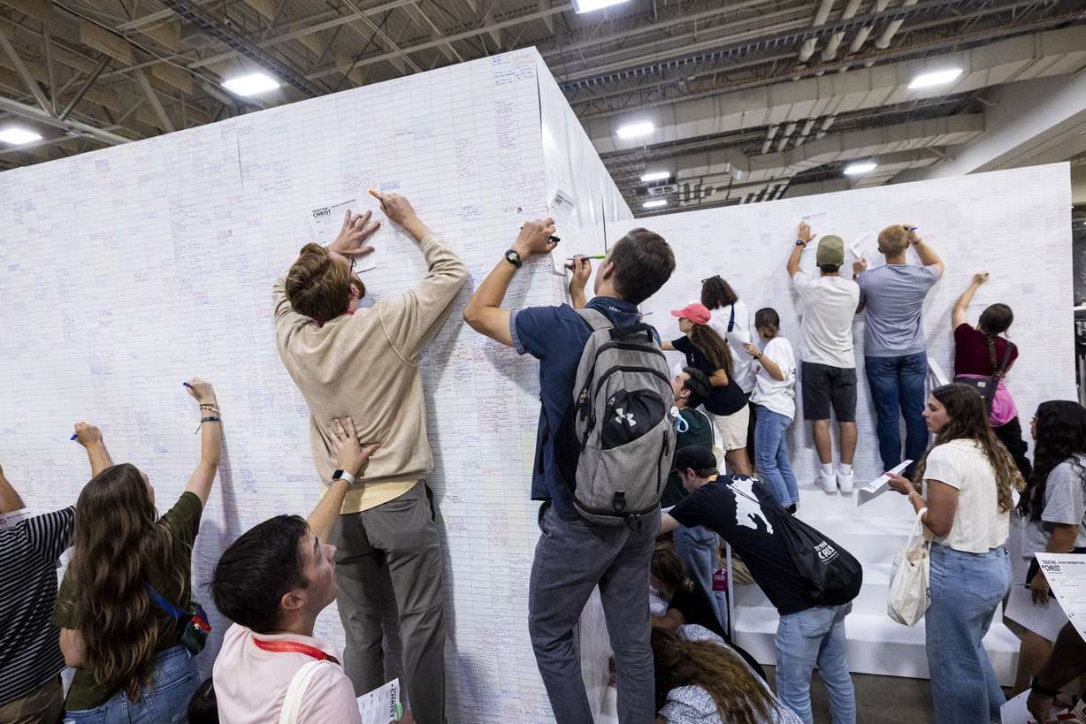Attendees sign a giant birthday card for President Russell M. Nelson’s upcoming 100th birthday during the 2024 Utah Area Young Single Adult Conference held at the Salt Palace Convention Center in Salt Lake City on Saturday.