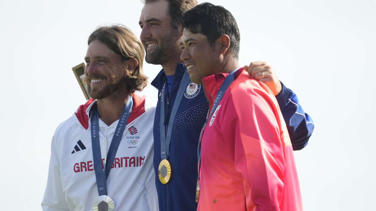 Gold medalist Scottie Scheffler, of the United States, centre, with Tommy Fleetwood, of Britain, silver medal, and Hideki Matsuyama, of Japan, with the bronze medal pose for the media following the medal ceremony for men's golf at the 2024 Summer Olympics, Sunday, Aug. 4, 2024, at Le Golf National in Saint-Quentin-en-Yvelines, France.