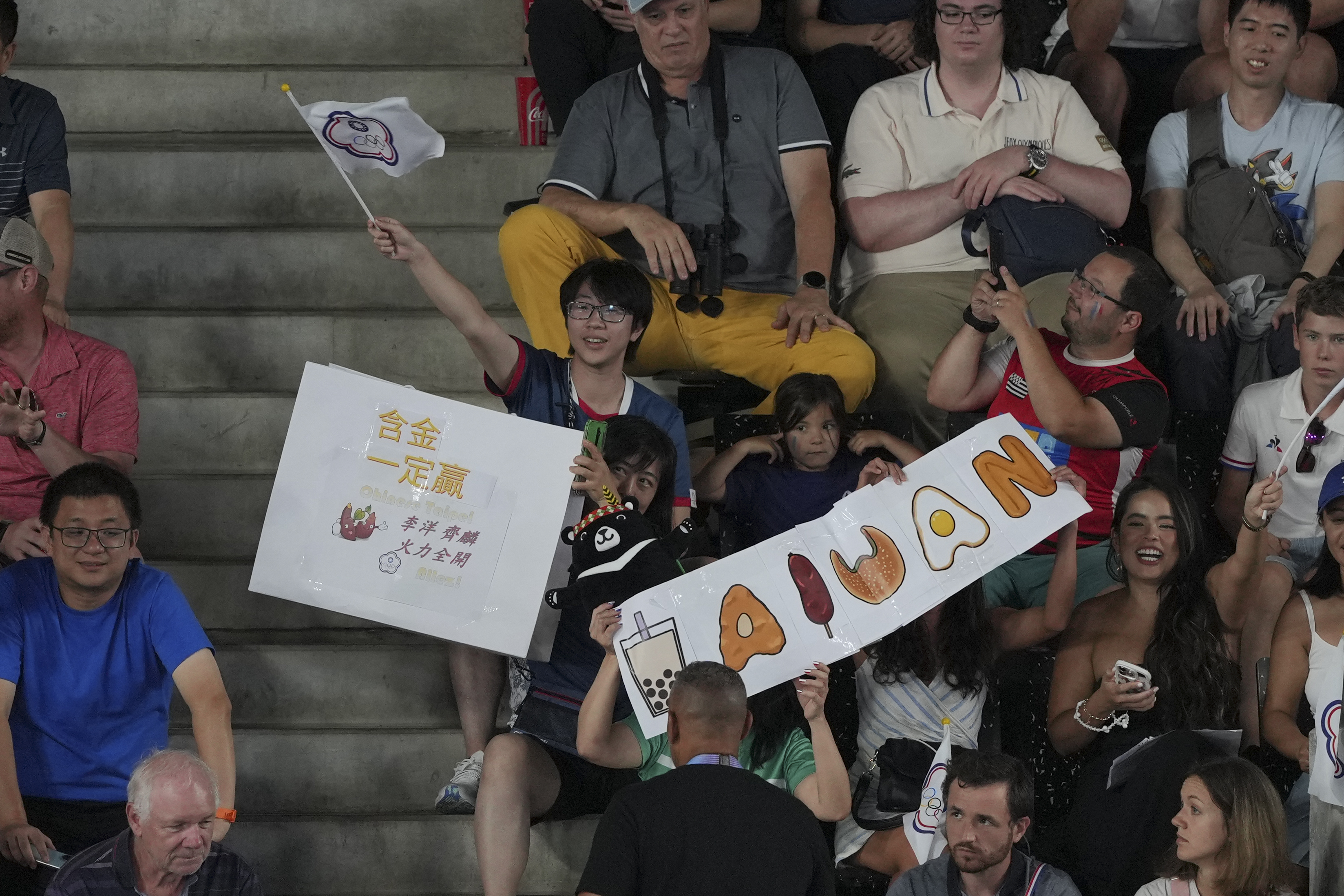 A fan hold a sign that reads "Sure Win" during the men's doubles gold medal match between China and Taiwan, at the 2024 Summer Olympics, Sunday, Aug. 4, 2024, in Paris, France. 