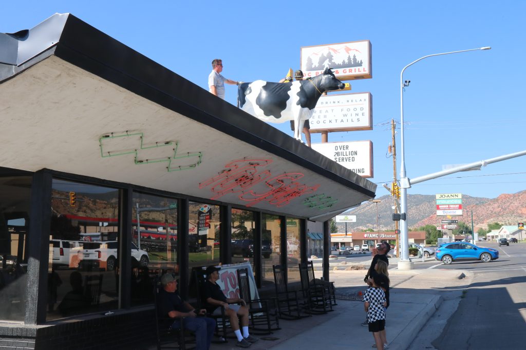 Workers prepare to lower an iconic fiberglass cow from the roof of the Top Spot Drive Inn building, Cedar City, July 31.