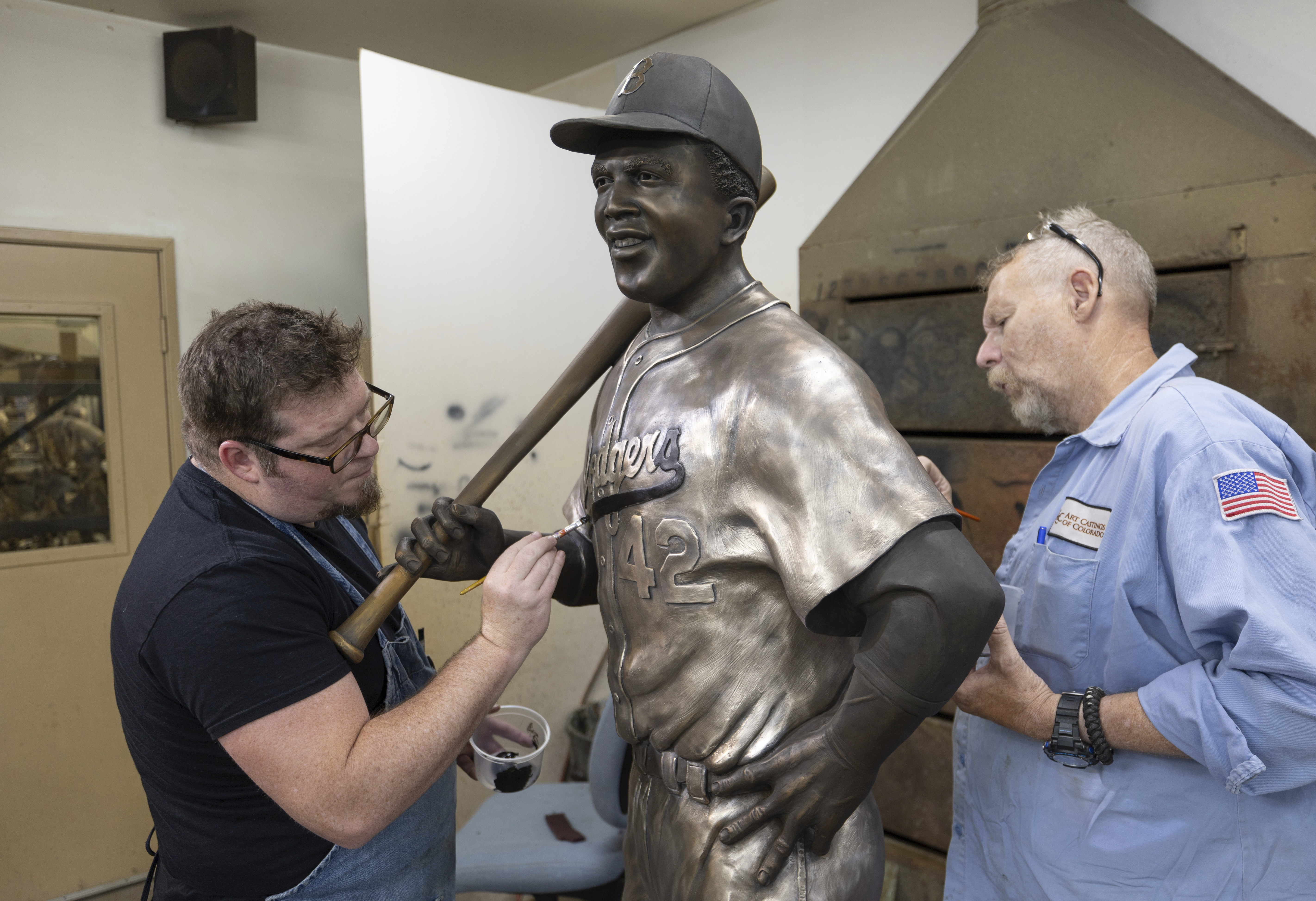 Nate Ford, left, and Jeff Herndon apply finishing touches to a statue of baseball hall-of-famer and civil rights pioneer Jackie Robinson in Loveland, Colo., on Wednesday, July 24, 2024.