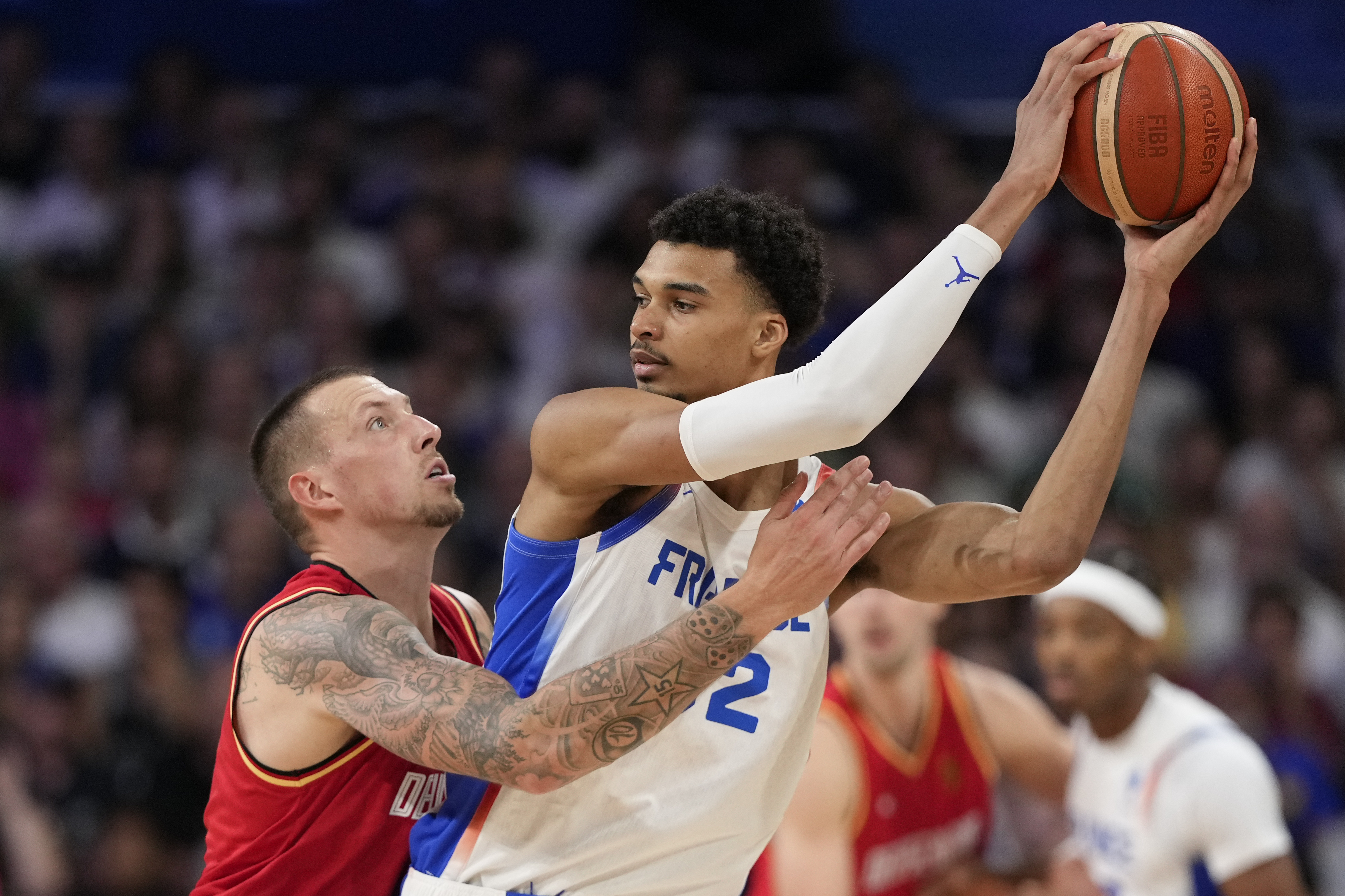 Daniel Theis, of Germany, reaches in on Victor Wembanyama, of France, in a men's basketball game at the 2024 Summer Olympics, Friday, Aug. 2, 2024, in Villeneuve-d'Ascq, France. 