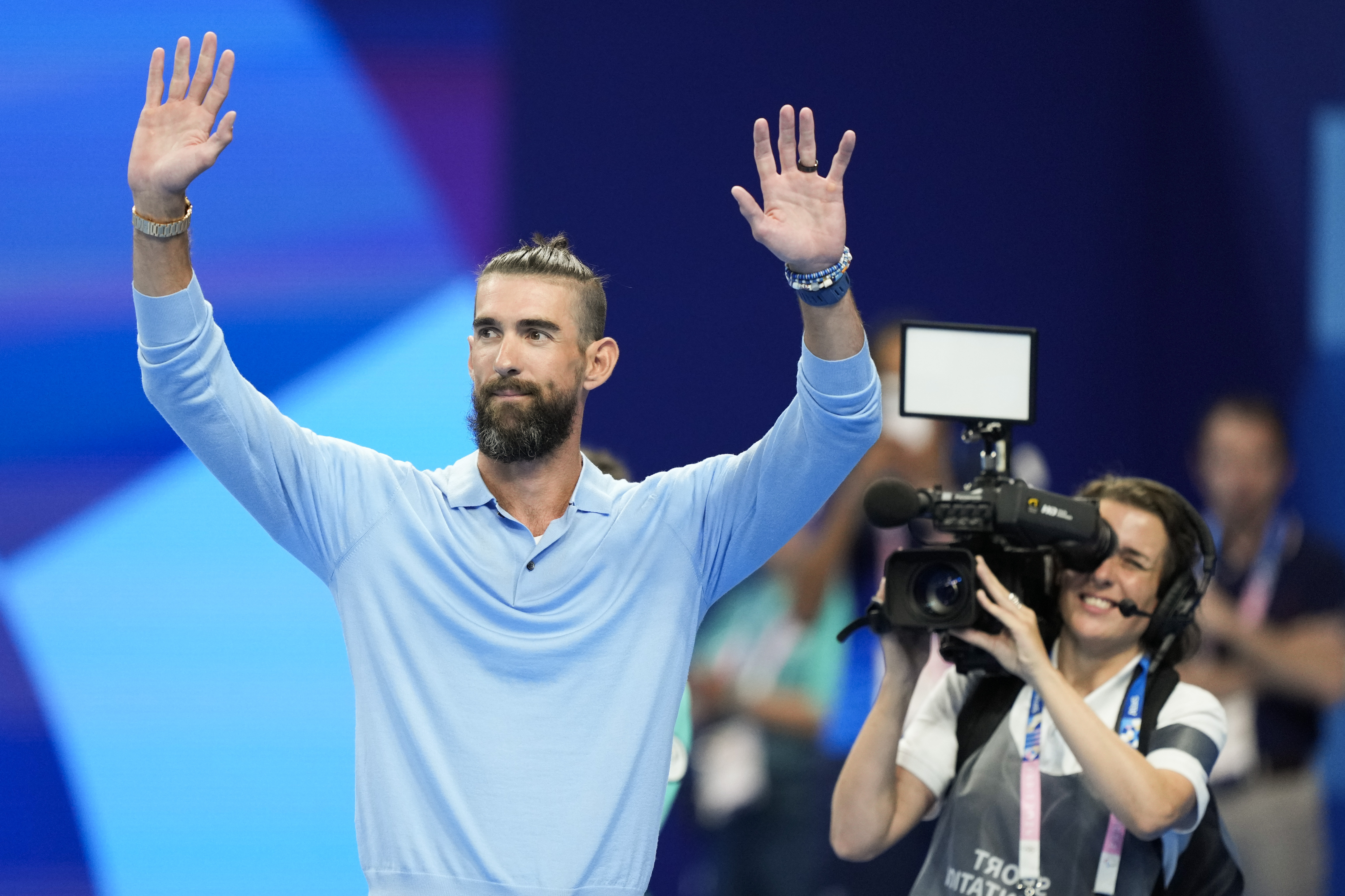 Former Olympic champion Michael Phelps, from the United States, waves to fans ahead of the evening swimming session at the 2024 Summer Olympics, Sunday, July 28, 2024, in Nanterre, France. 
