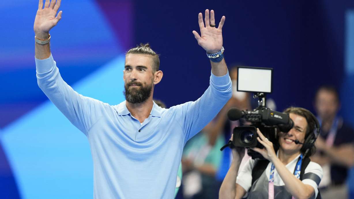 Former Olympic champion Michael Phelps, from the United States, waves to fans ahead of the evening swimming session at the 2024 Summer Olympics, Sunday, July 28, 2024, in Nanterre, France.