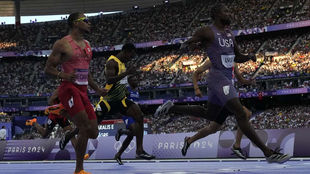 Noah Lyles, of the United States, crosses the finish line ahead of Andre de Grasse, left, of Canada, to win his men's 200-meters' heat at the 2024 Summer Olympics, Monday, Aug. 5, 2024, in Saint-Denis, France.